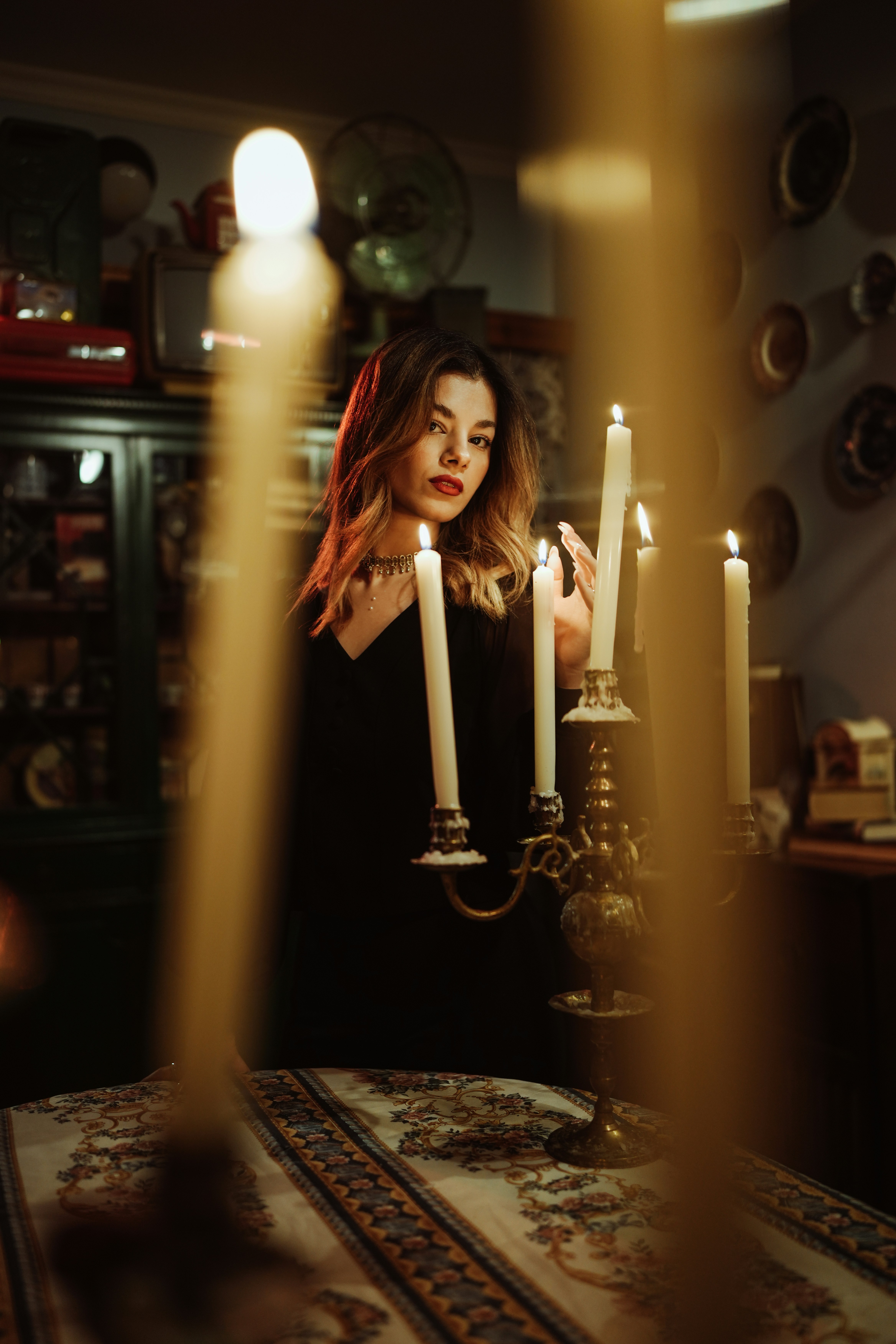 A woman in a black dress behind a candelabra with lit candles