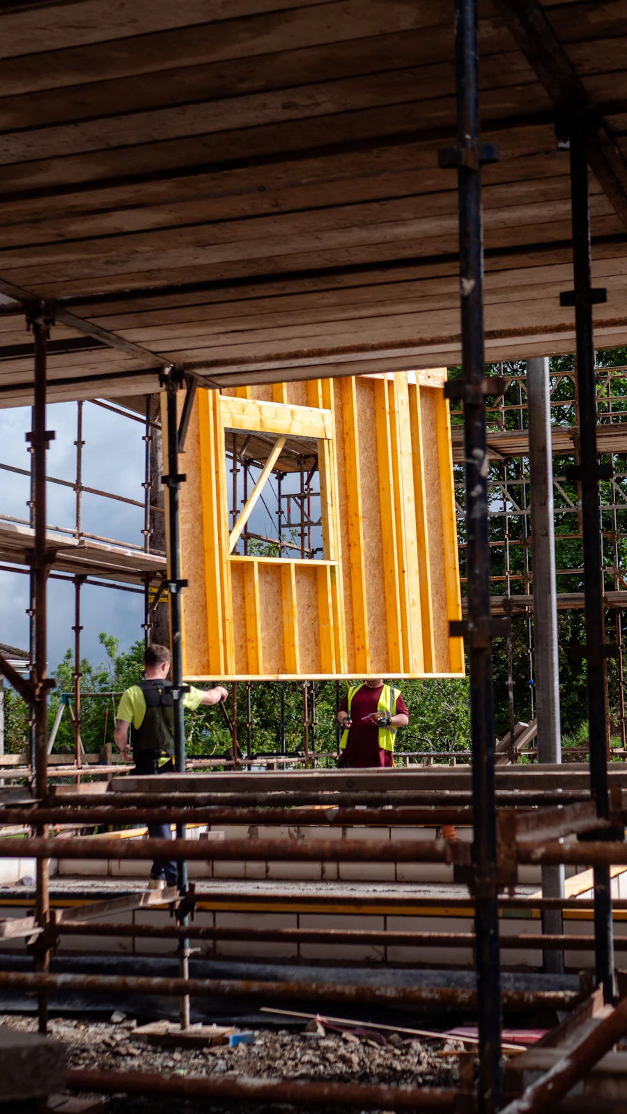 Two workers lifting a wood wall frame into place