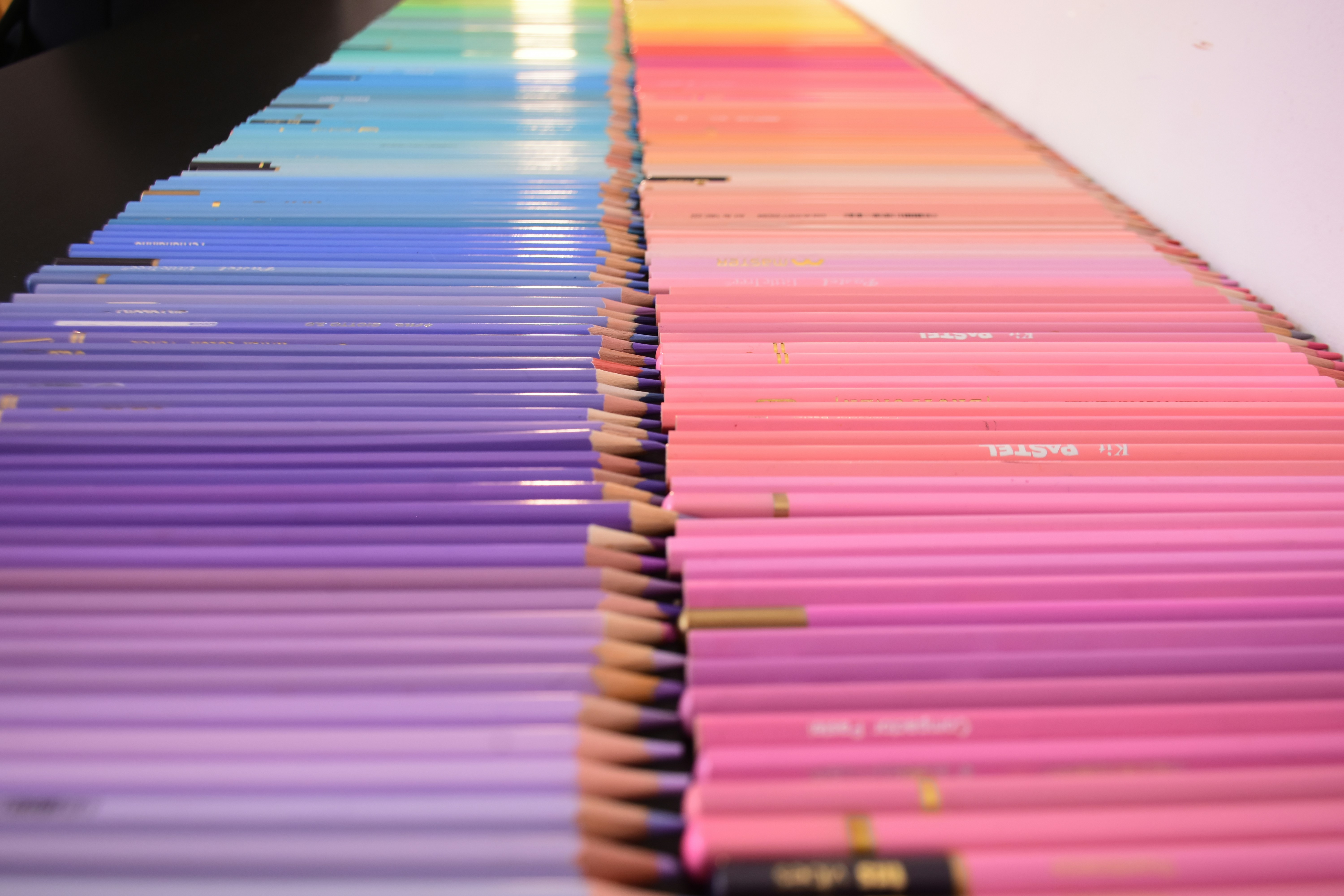 Rows of colored pencils arranged in a gradient from blue to pink