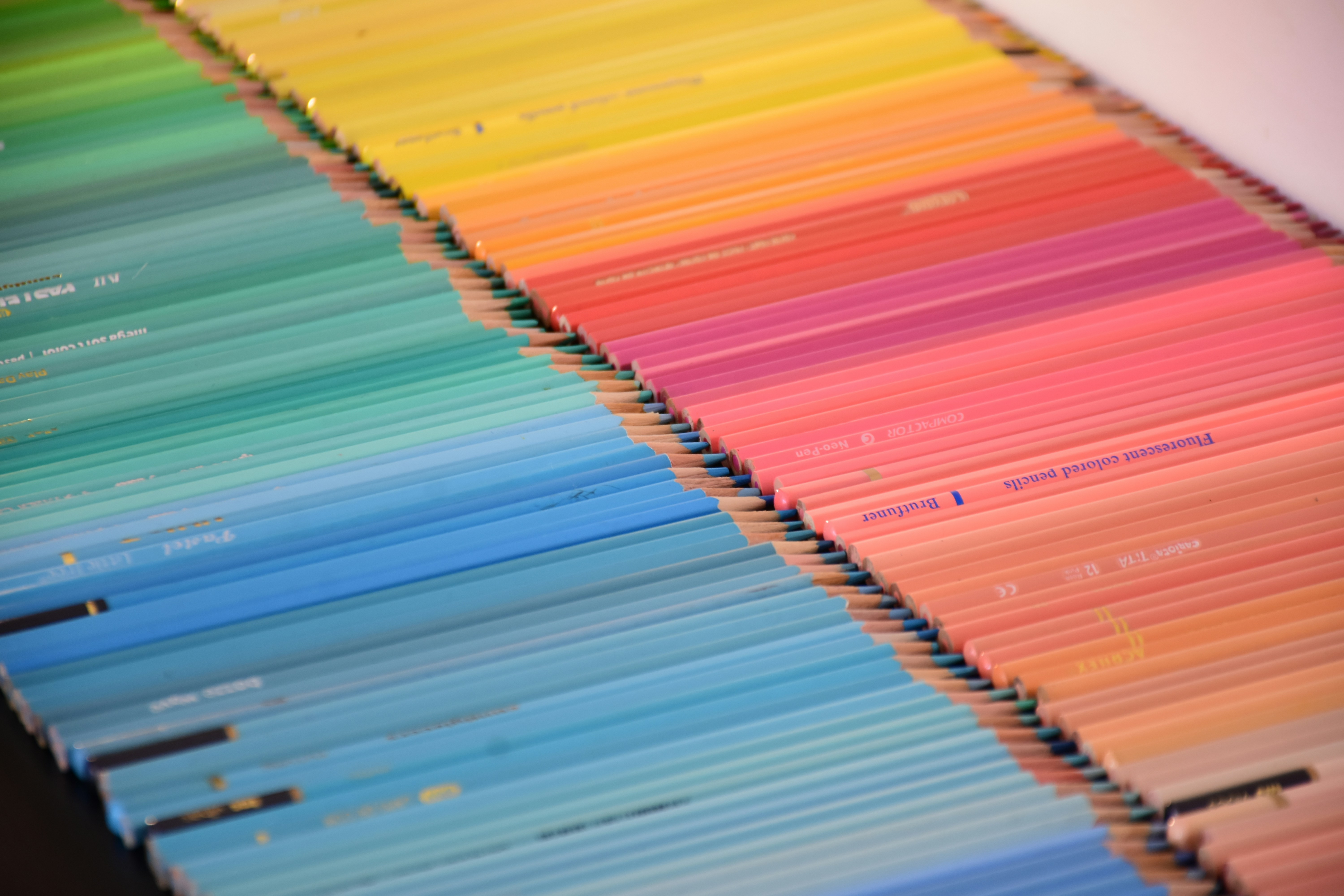 A large collection of colored pencils arranged in a vibrant rainbow gradient pattern