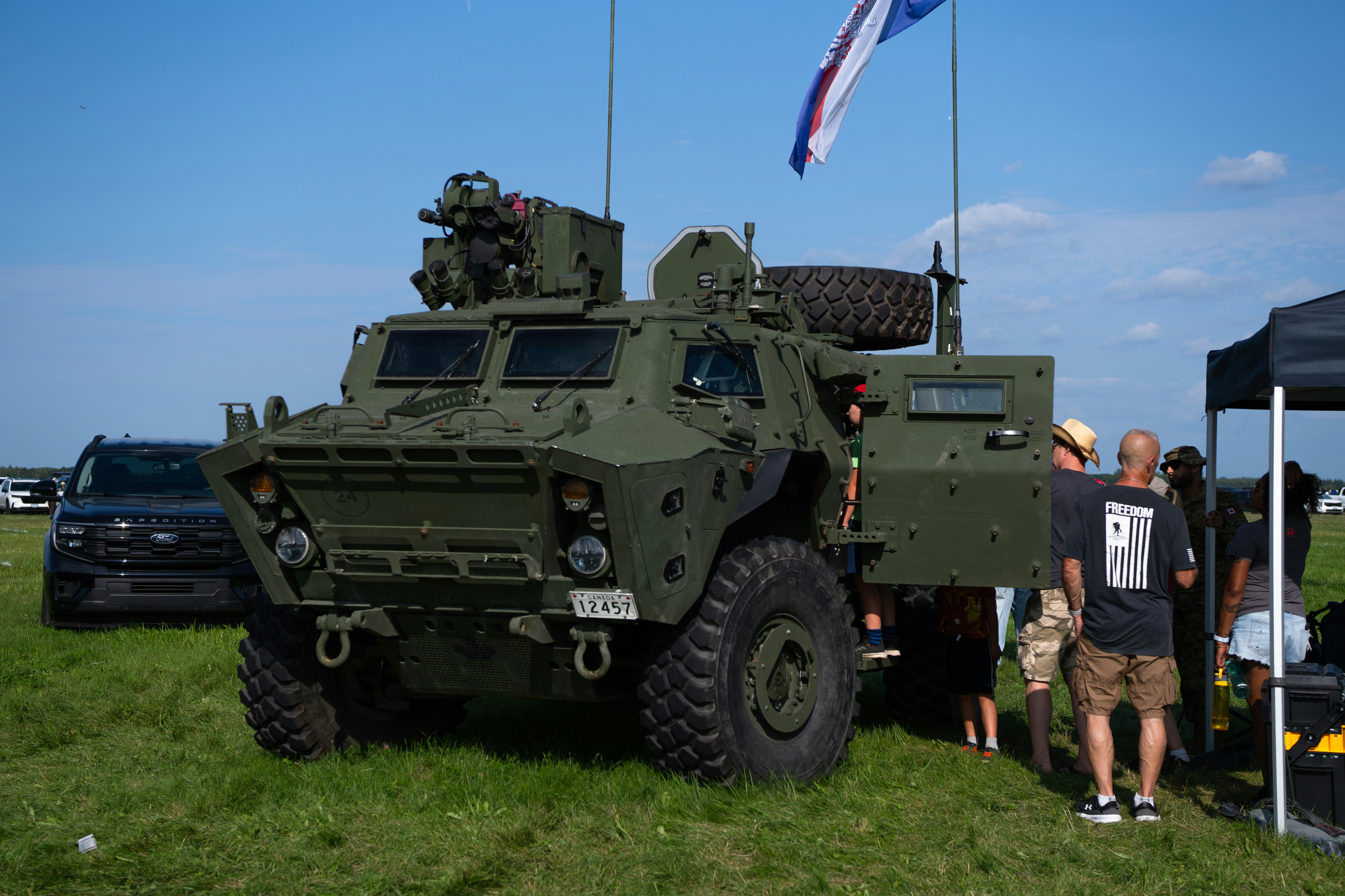 A green military armored vehicle with an open door on a grassy field