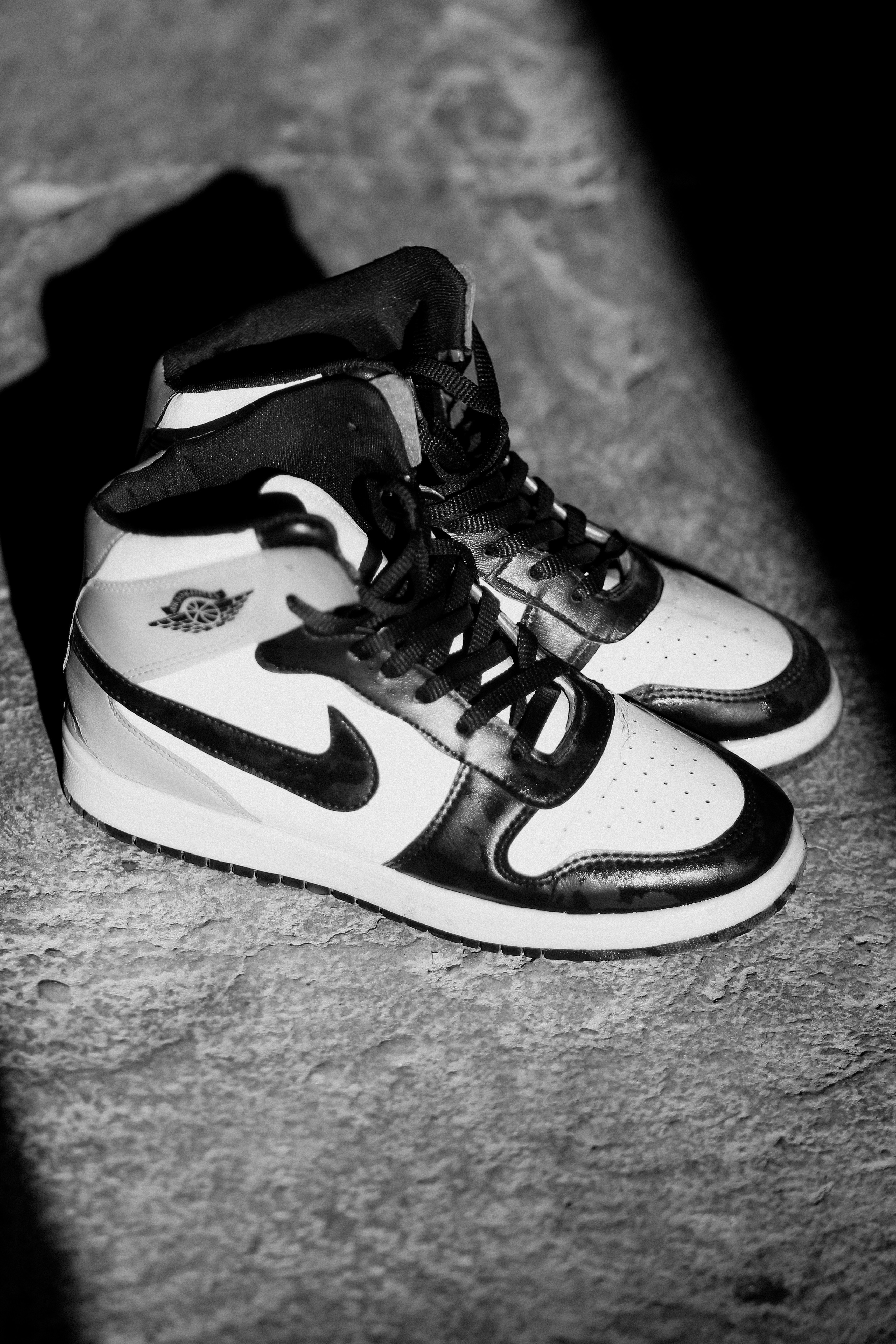 A pair of high-top sneakers with black and white panels on a concrete surface