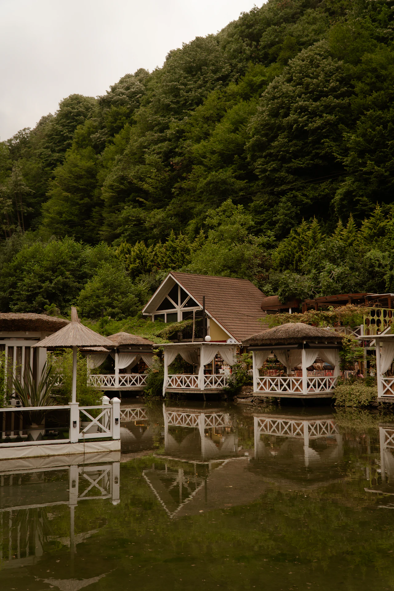 Pavilions on a pond below forested hills, Maşukiye