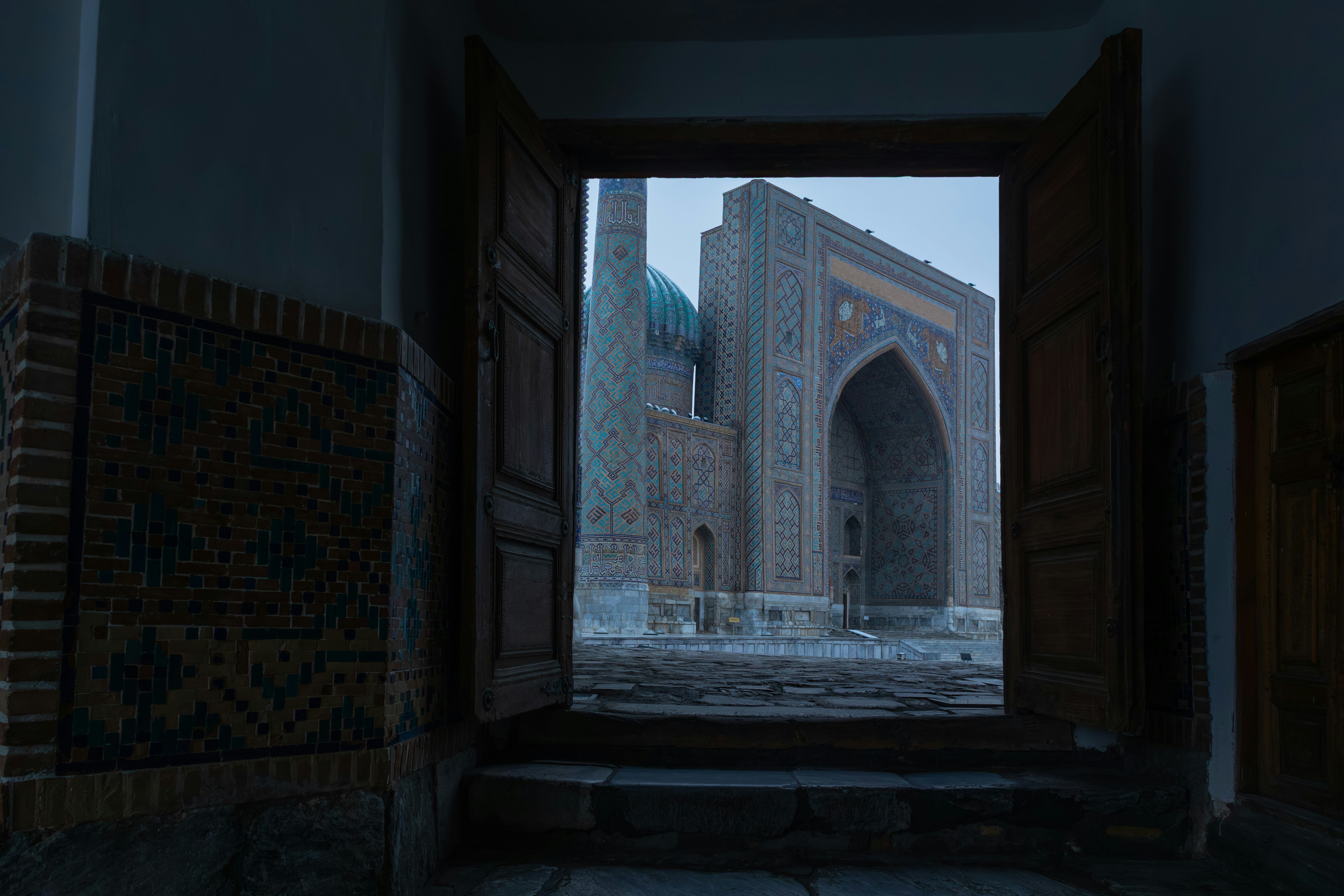 Registan square seen through a carved wooden doorway