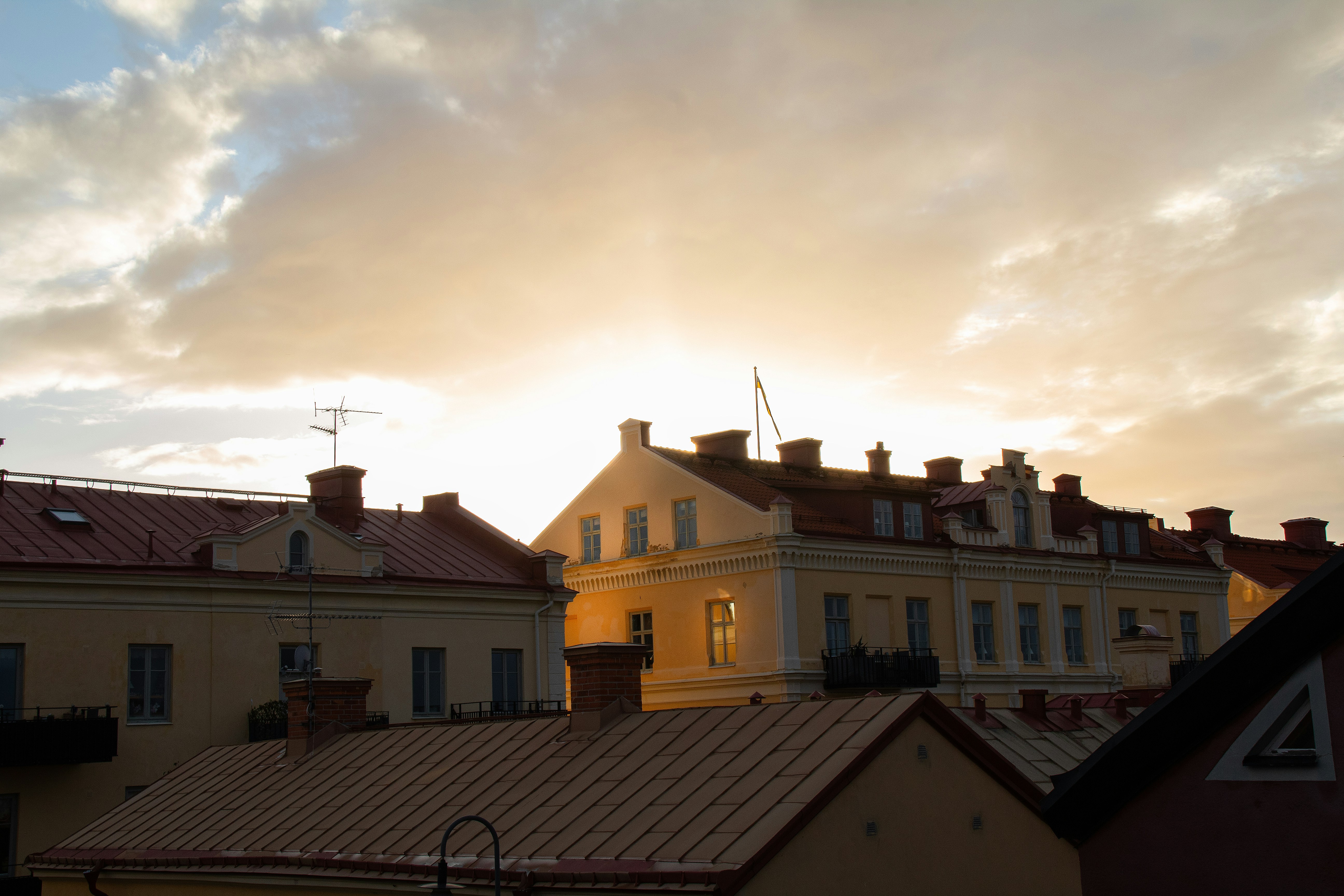 Yellow buildings with red roofs under a cloudy sky during golden hour