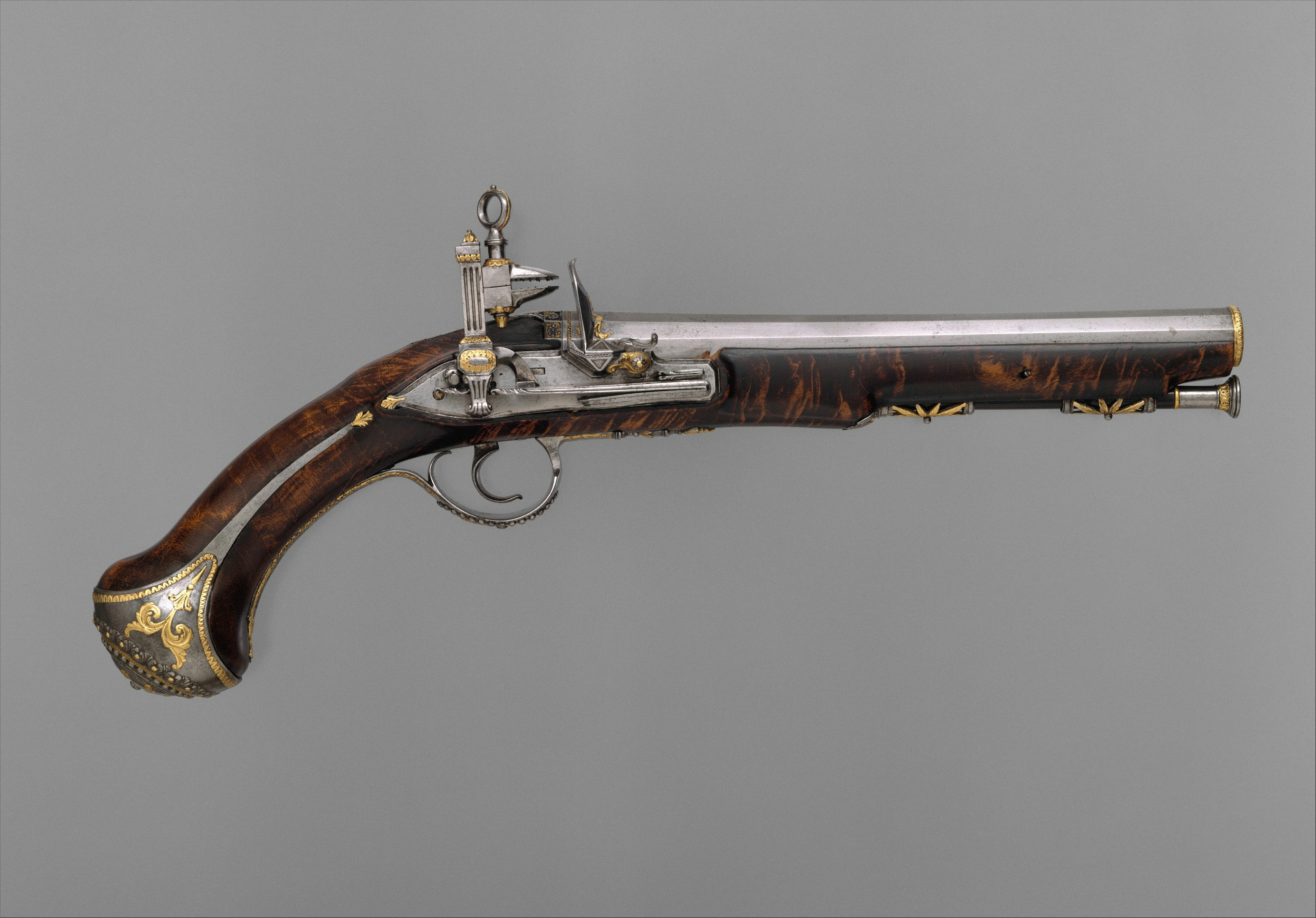 An ornate flintlock pistol with a dark wooden stock and gold metal inlay