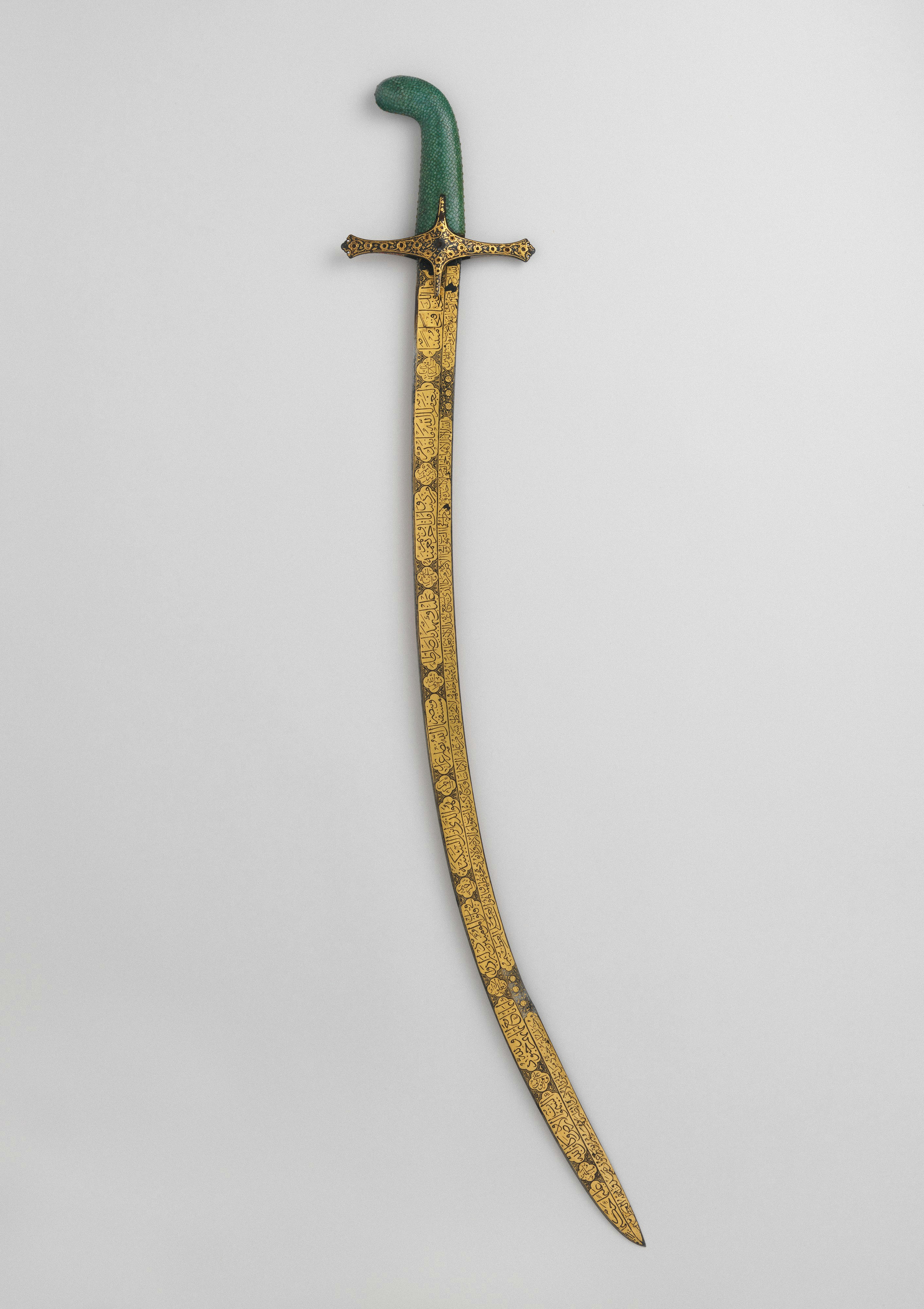 A curved sword with a green handle and gold blade inscribed with calligraphy