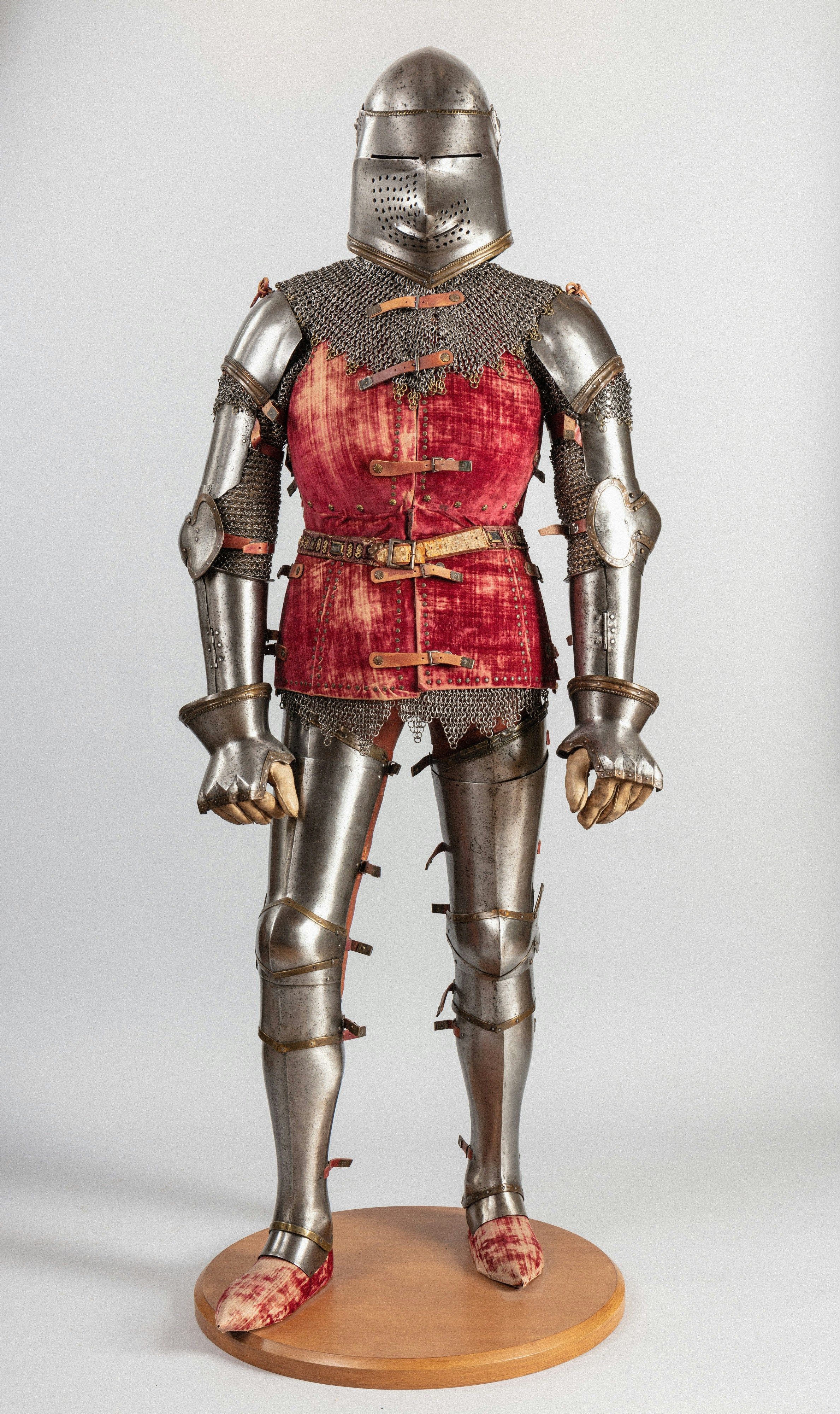A full suit of steel plate armor with a red velvet doublet