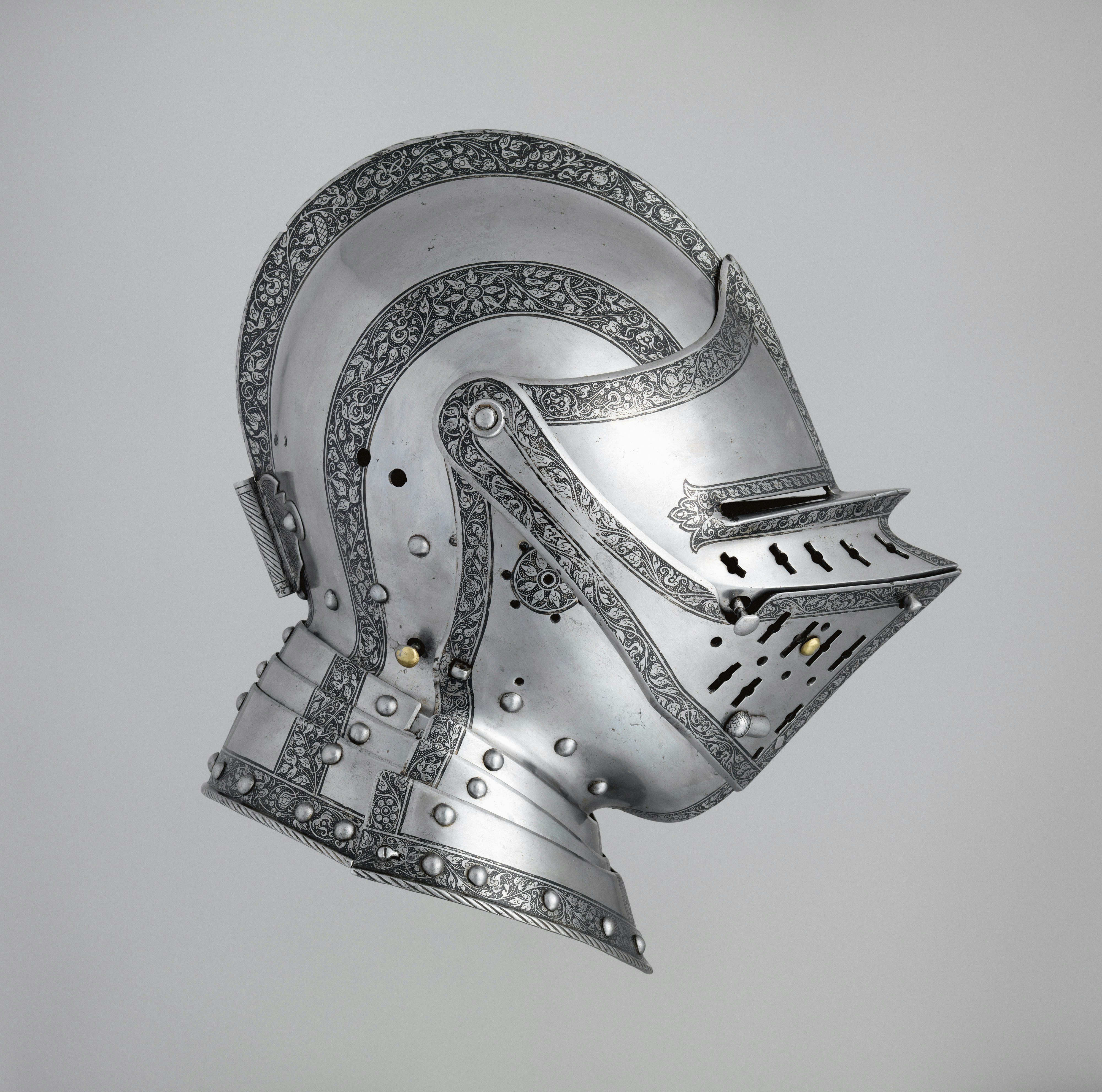 deflector: A polished steel knight helmet with intricate floral engravings on a grey background