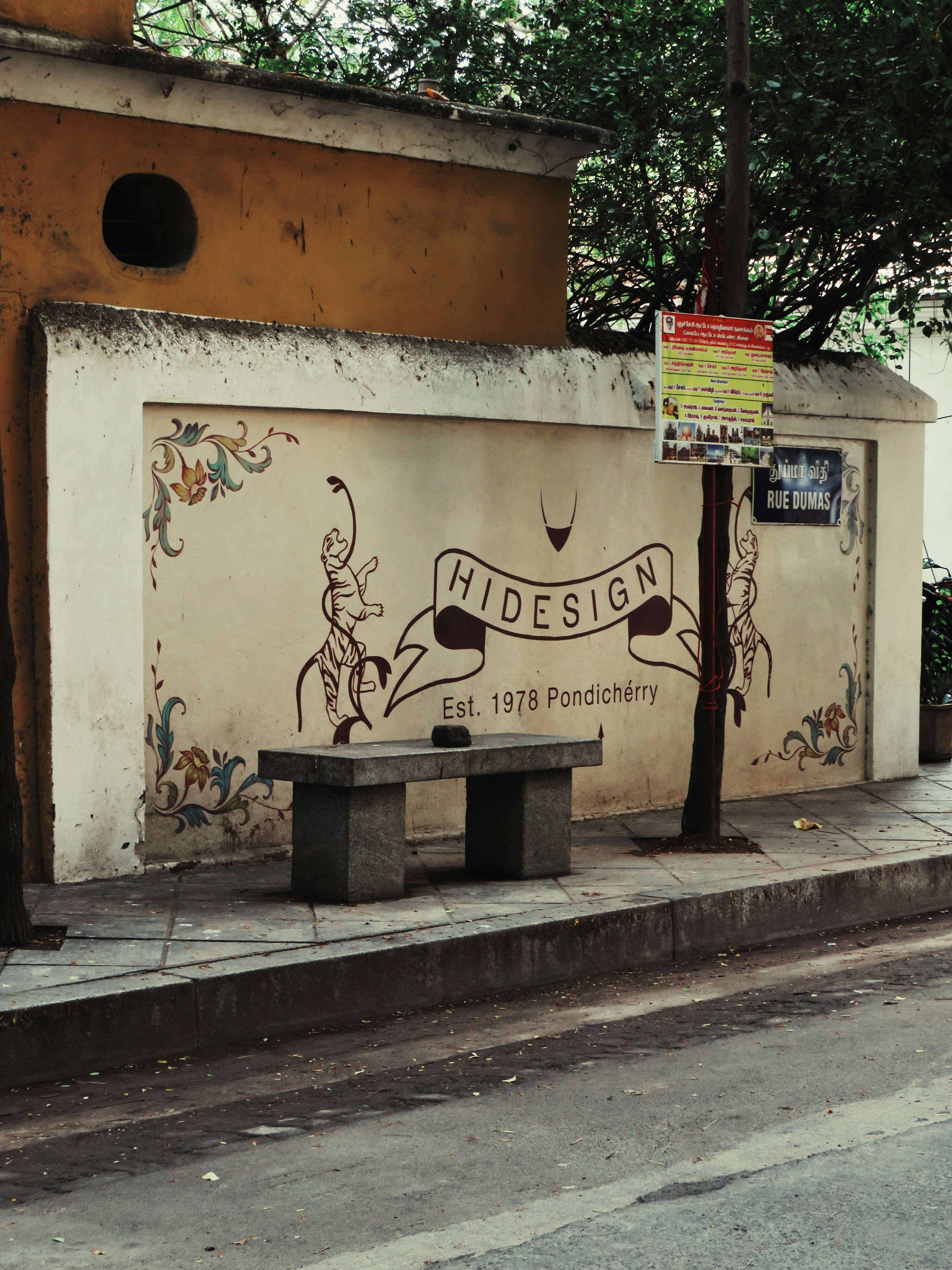 A stone bench in front of a wall with Hidesign branding in Pondicherry