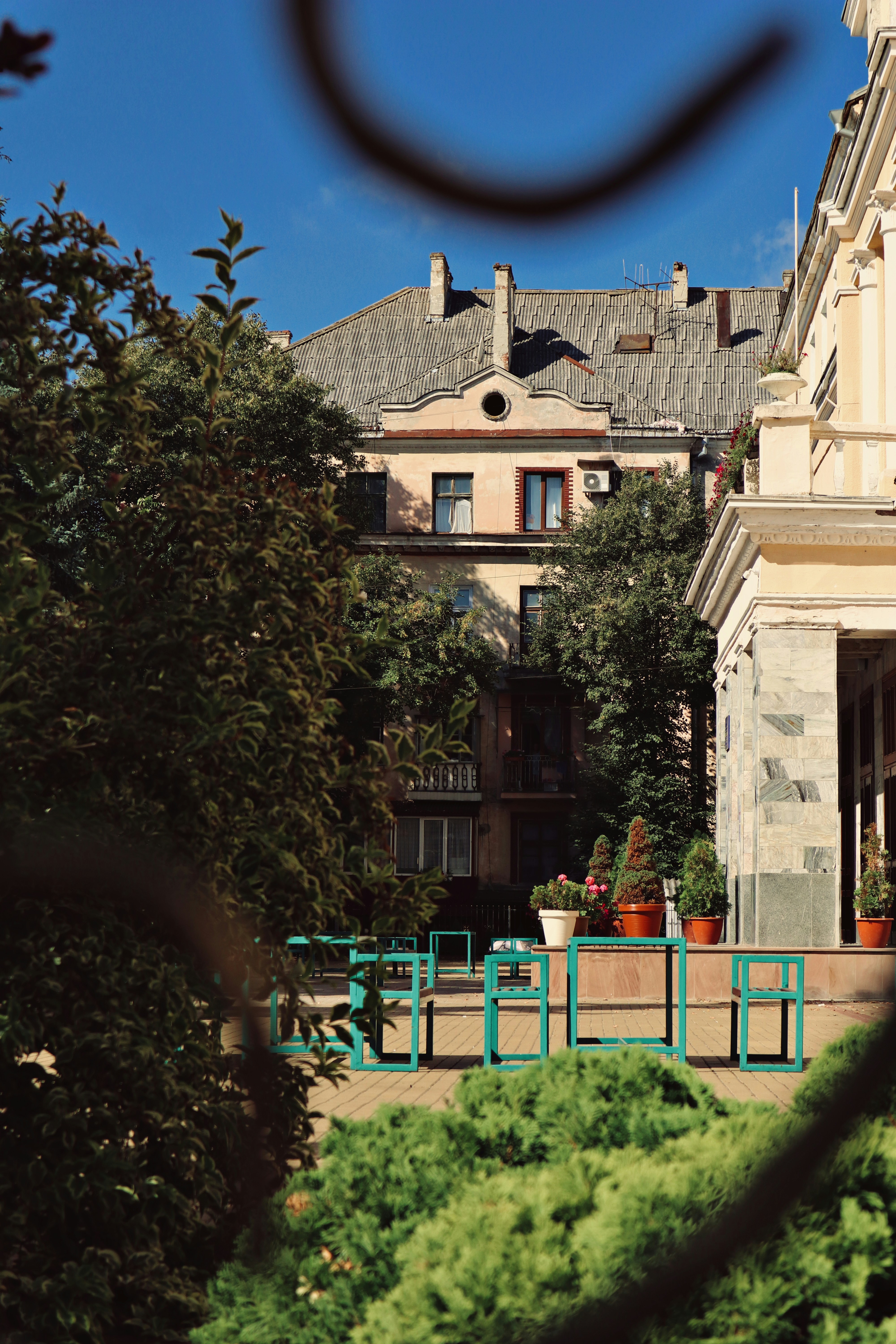 Teal metal chairs and tables on a paved patio before a historic building