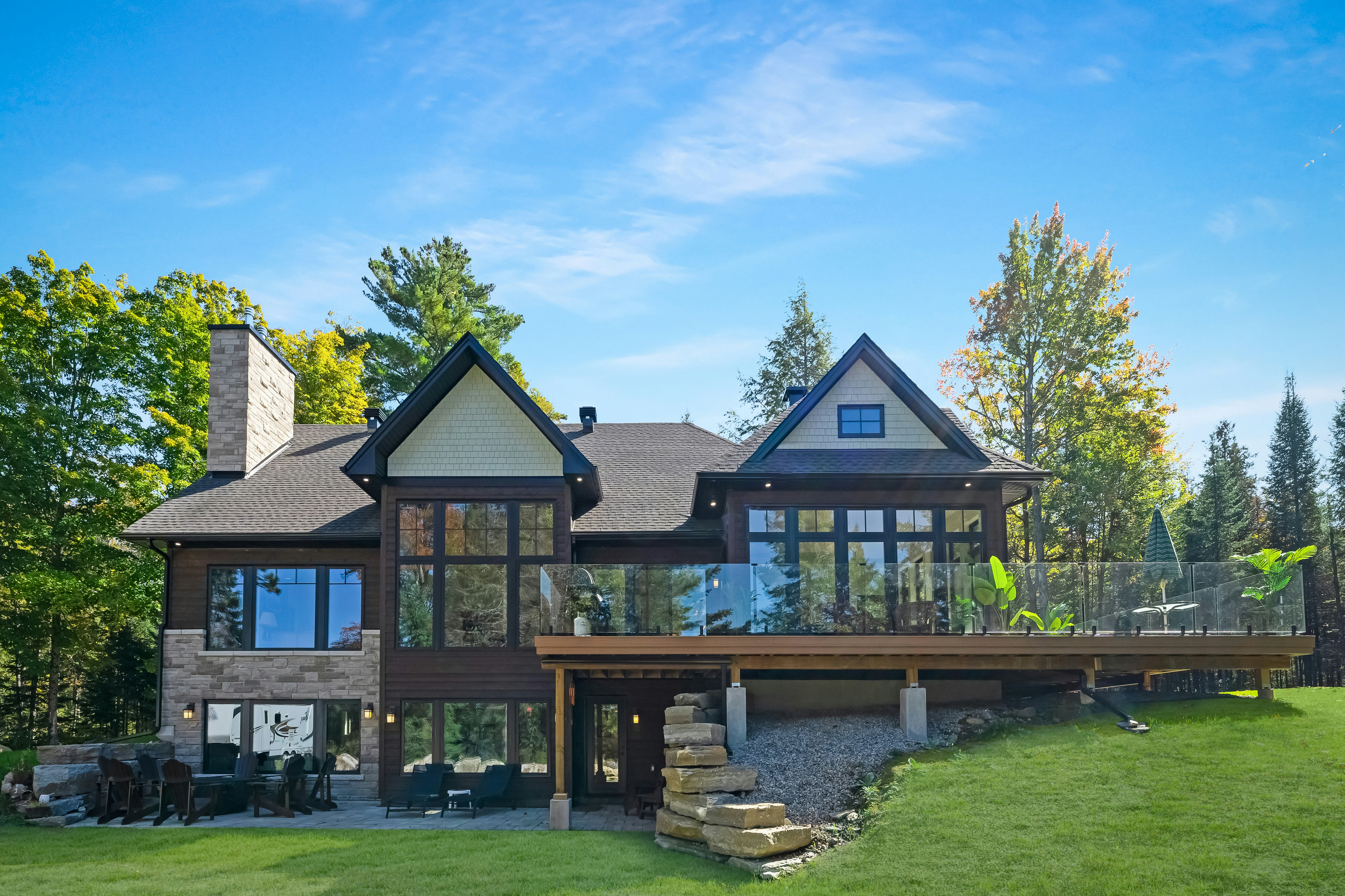 Beautifully finished home exterior renovation with wooden deck and stone patio