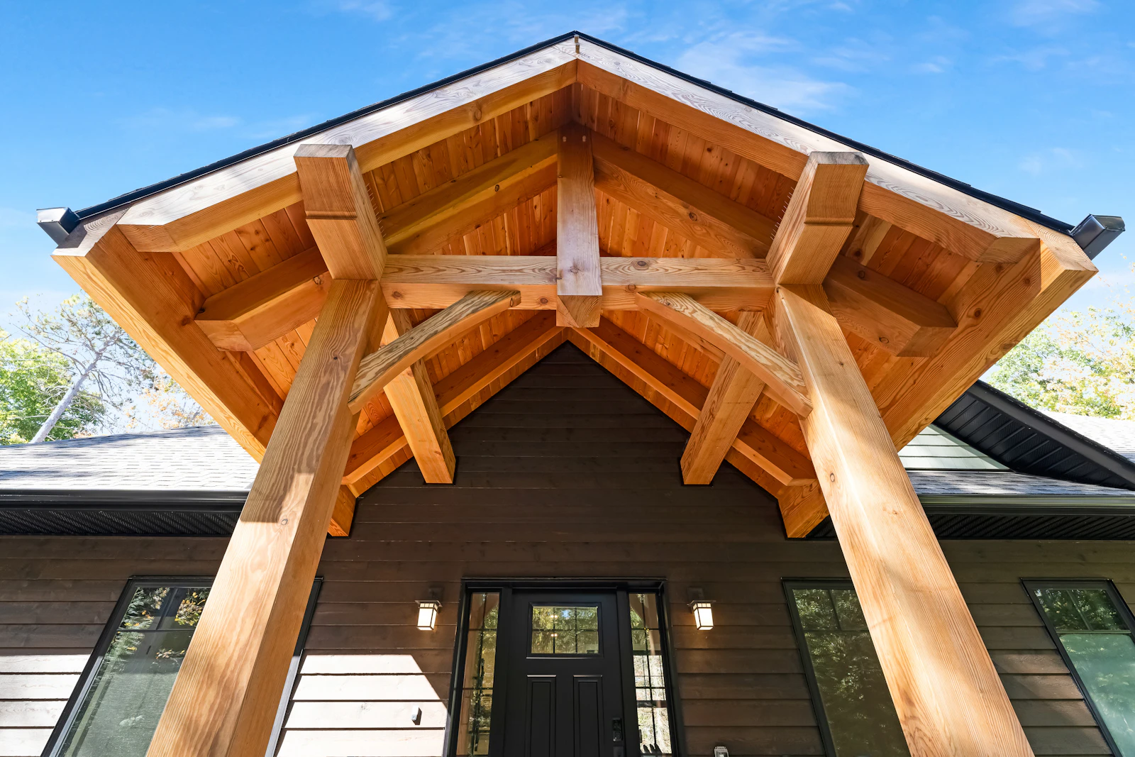 A heavy timber-frame entry porch on a dark-sided modern home