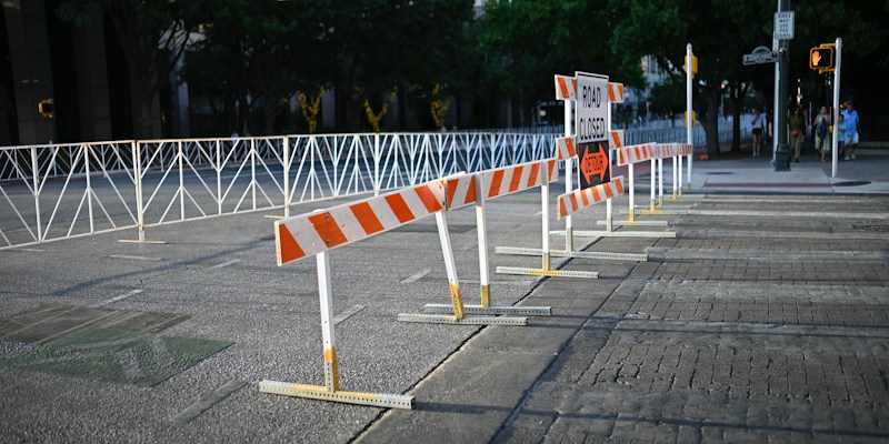 Orange and white striped road barriers blocking a downtown city street intersection