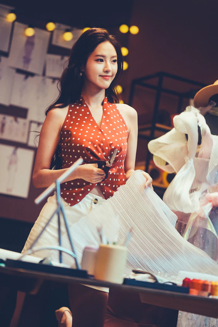 A dressmaker cutting white fabric in a studio