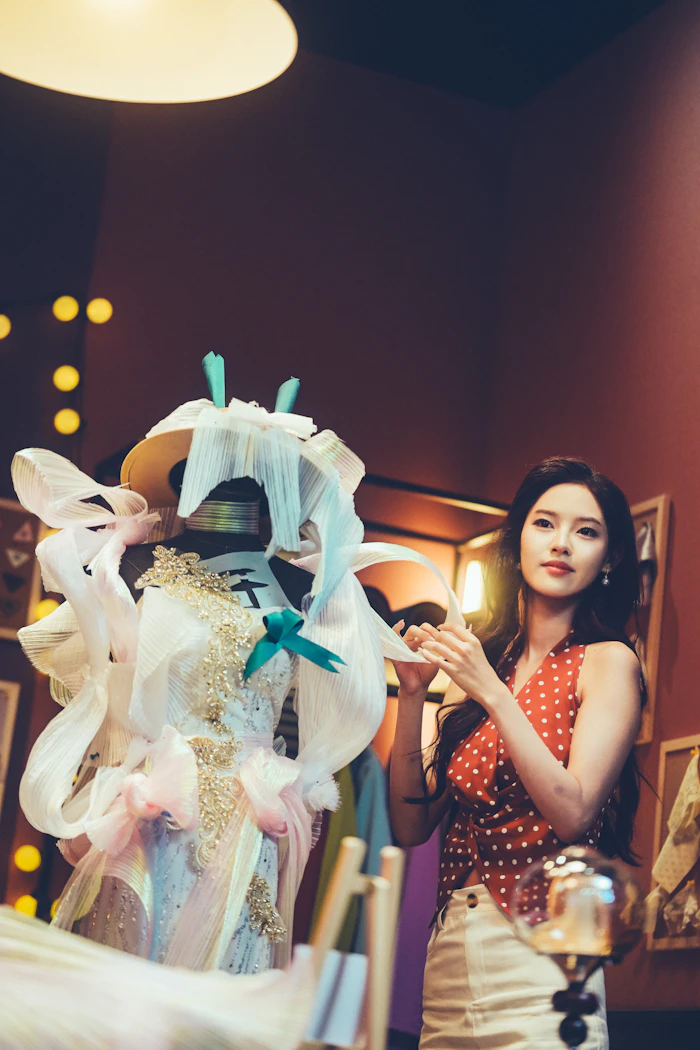 A dressmaker adjusting a white dress on a mannequin