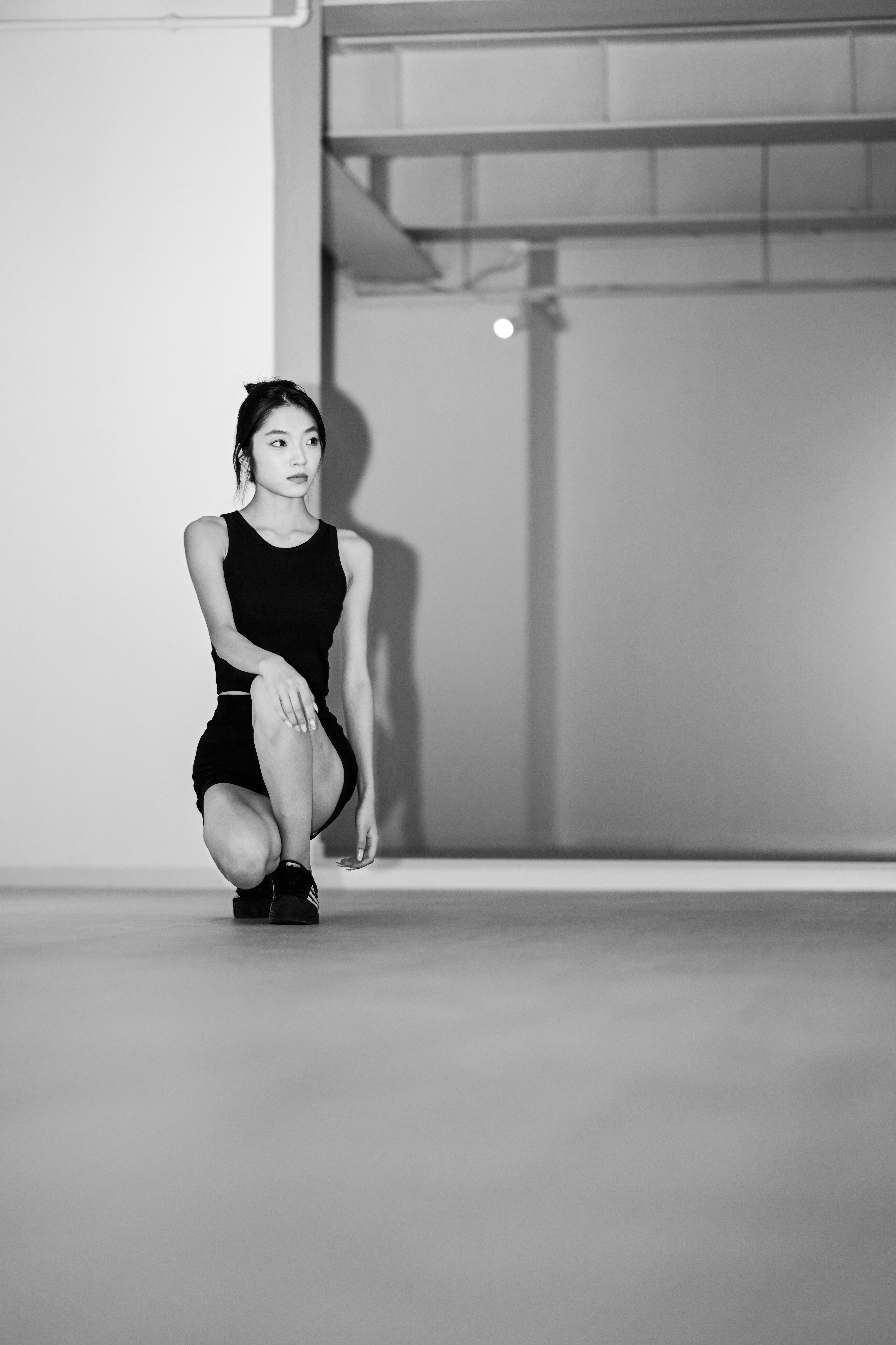 Une femme en débardeur noir et short agenouillée dans un atelier