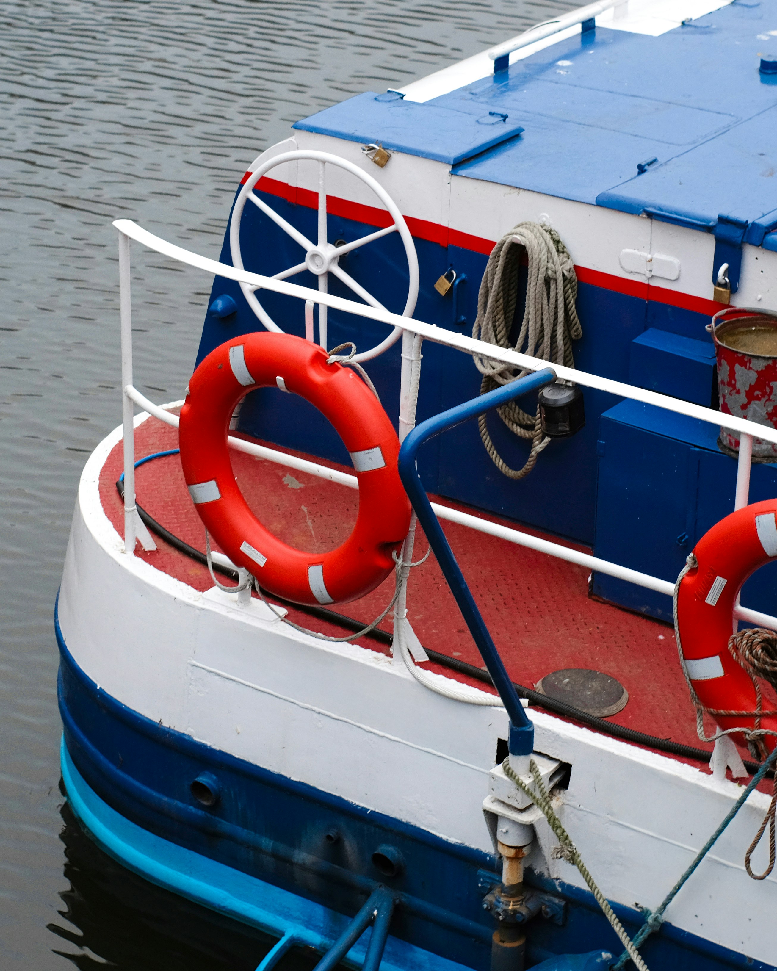 A red lifebuoy on the white railing of a blue and white boat