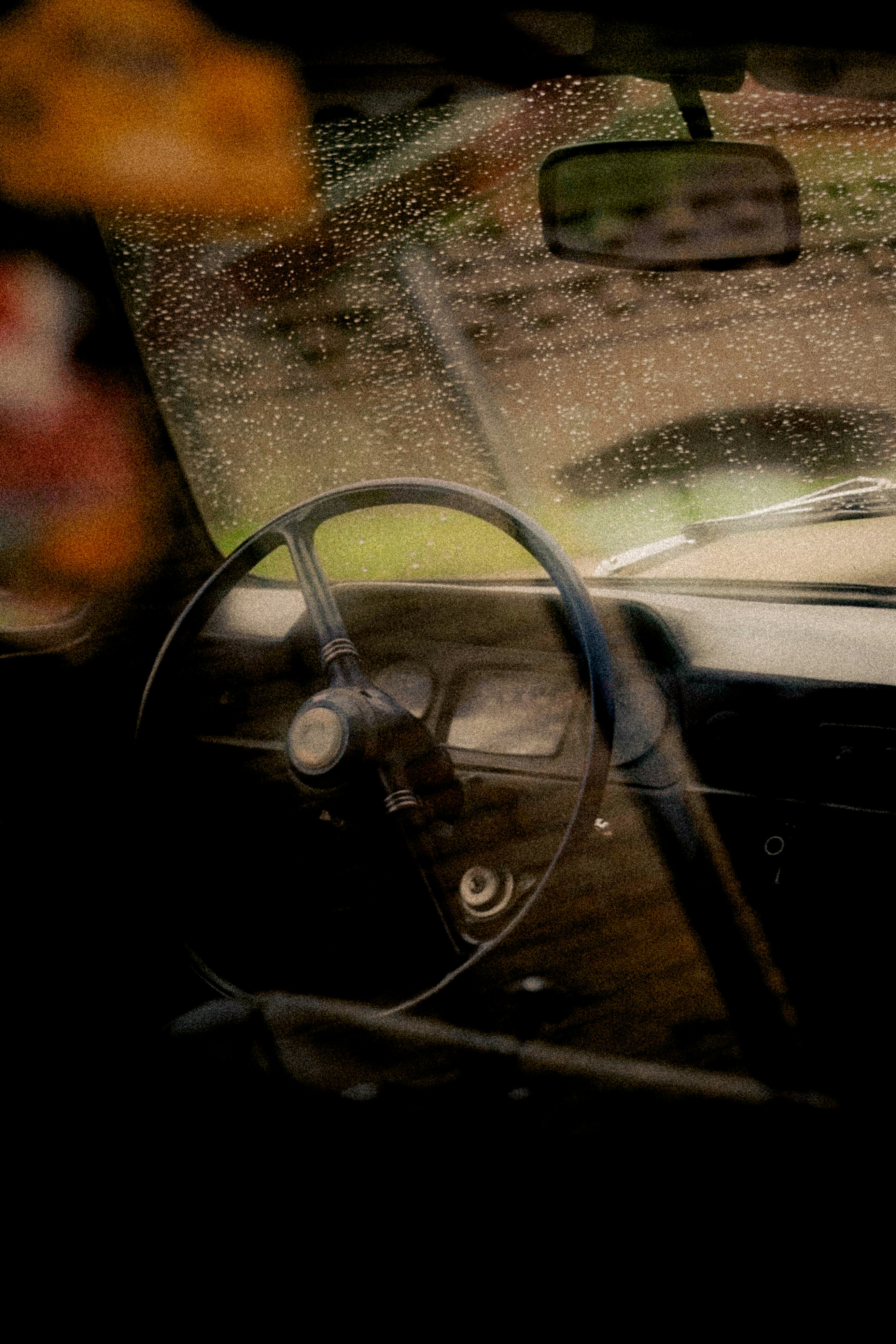 The interior of a vintage car with raindrops on the windshield