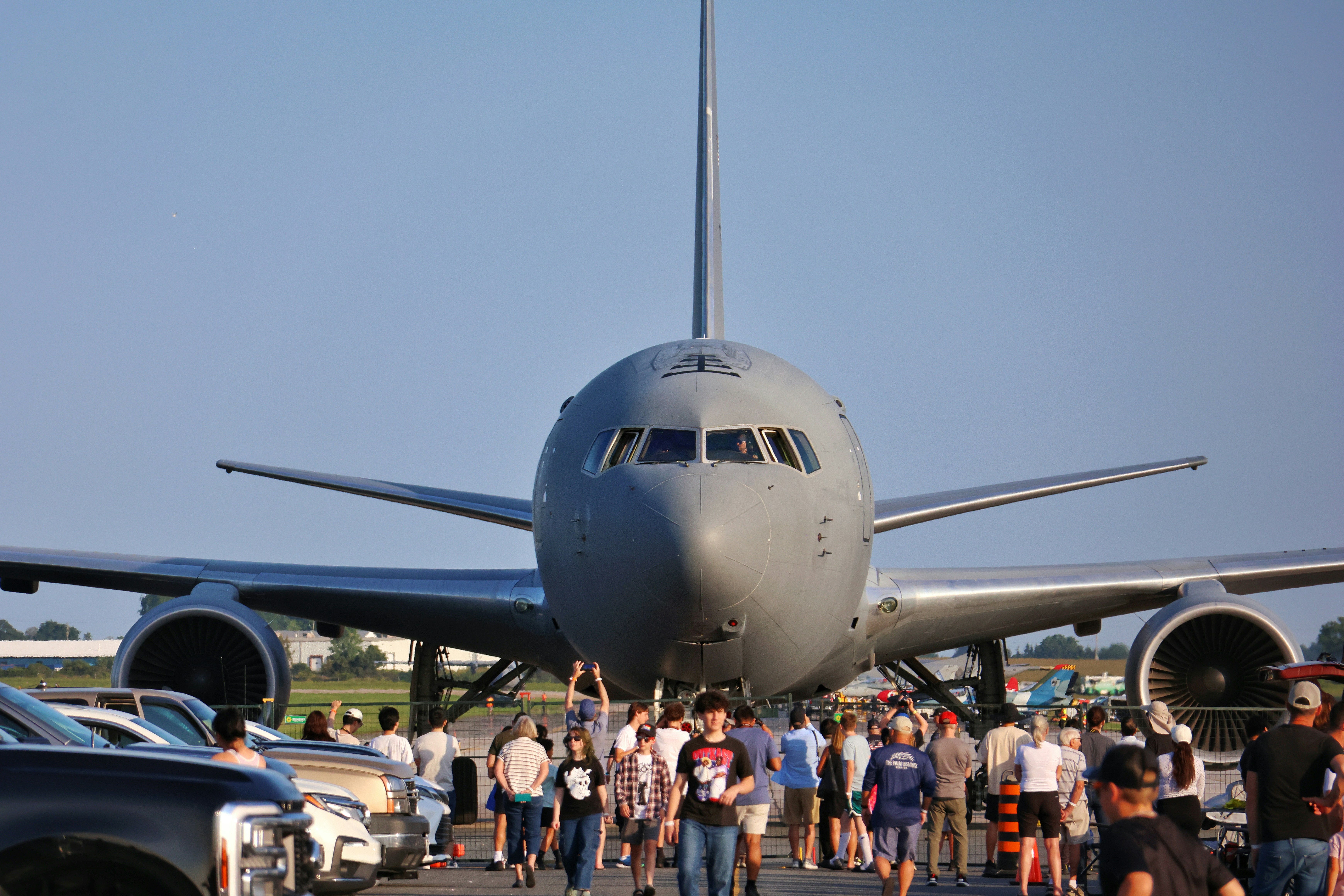 Eine Menschenmenge steht vor einem großen grauen Militärflugzeug auf einer Start- und Landebahn