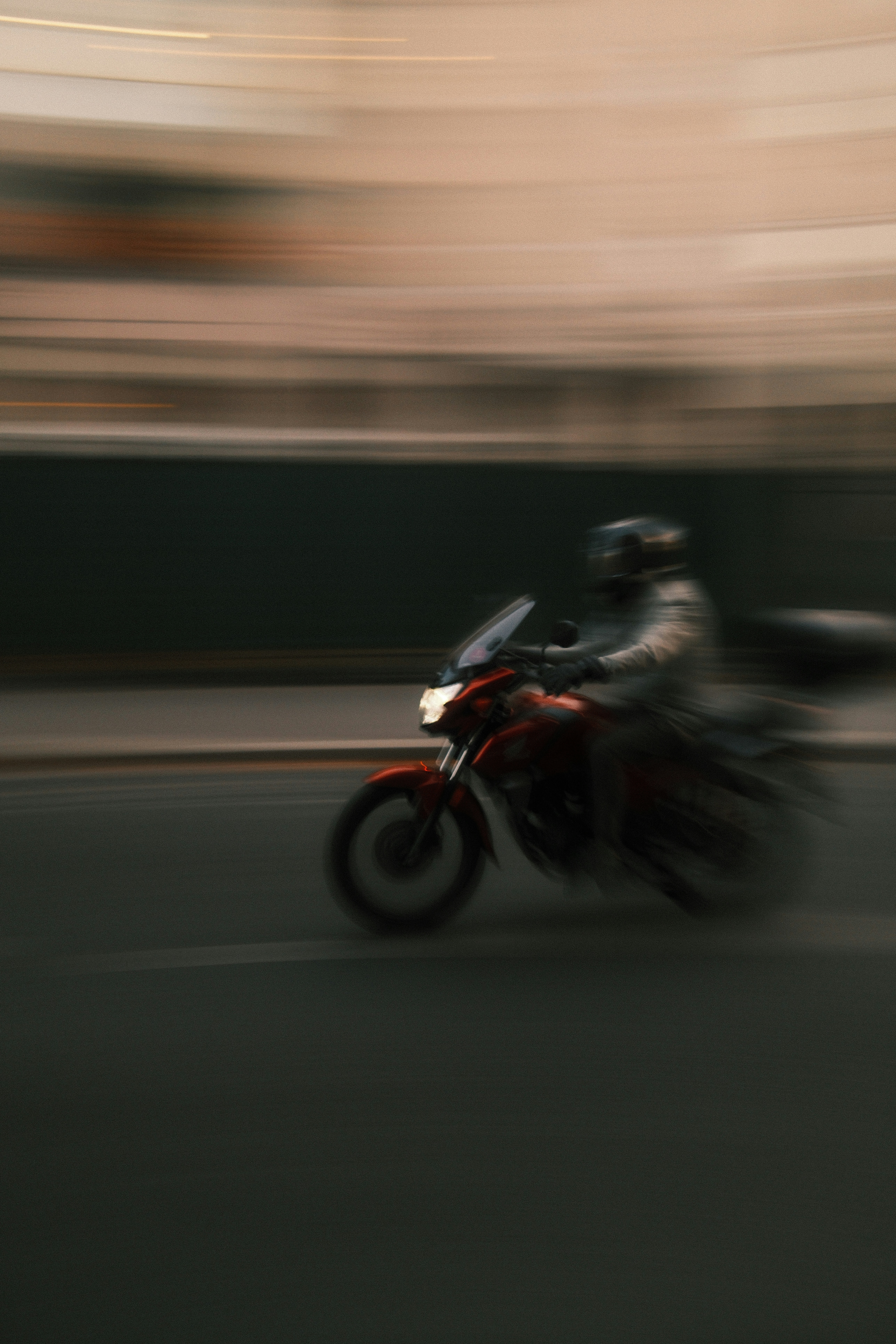 A person riding a red motorcycle in motion on a city street - 相关推荐
