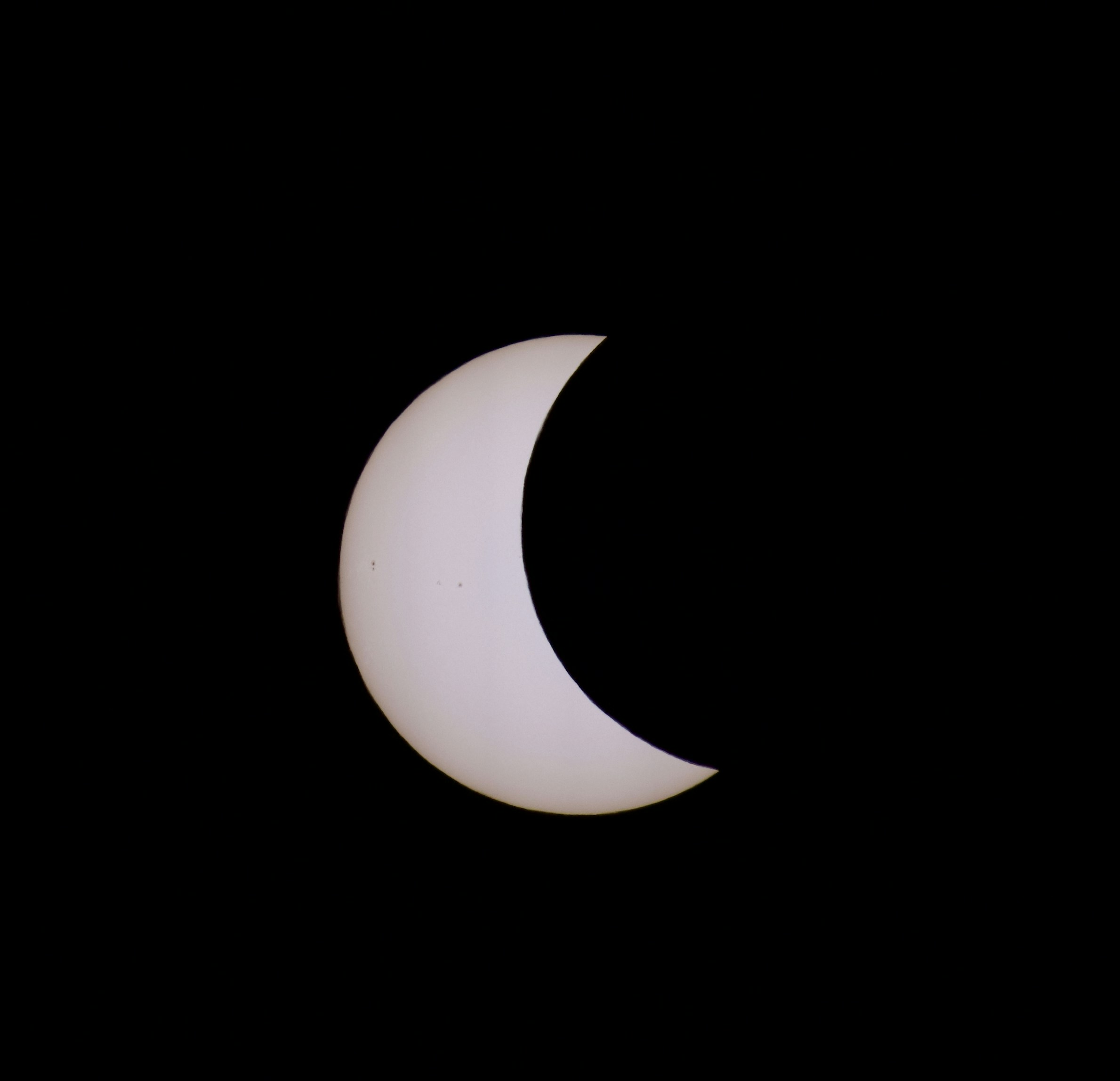 Eine Sichel, die teilweise vom Mond vor einem schwarzen Himmel verfinstert wird