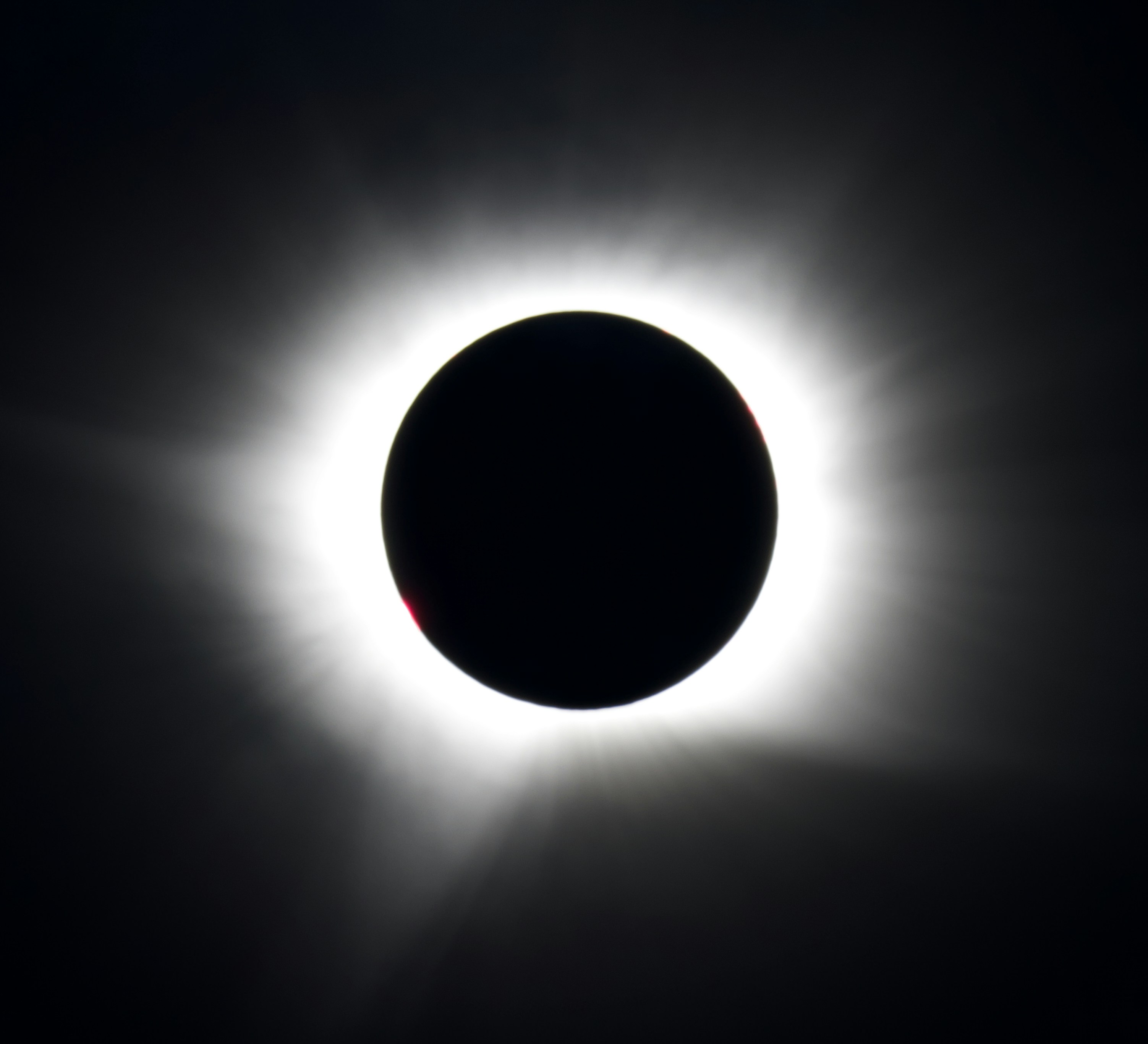 Eine totale Sonnenfinsternis mit einer hellweißen Korona, die einen dunklen Mond umgibt