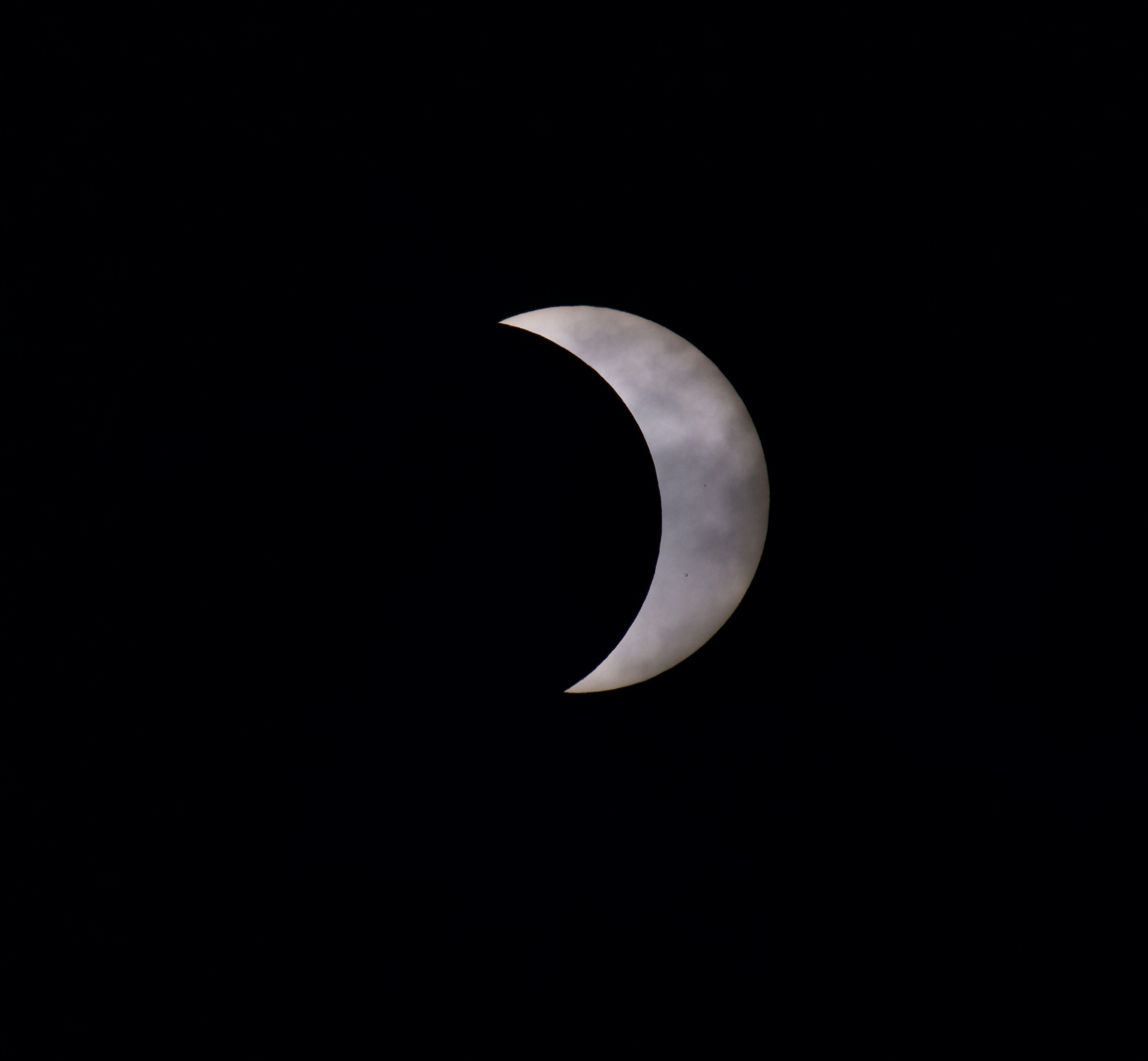 Ein Sichelmond, der teilweise von dünnen Wolken vor einem dunklen Nachthimmel verdeckt ist
