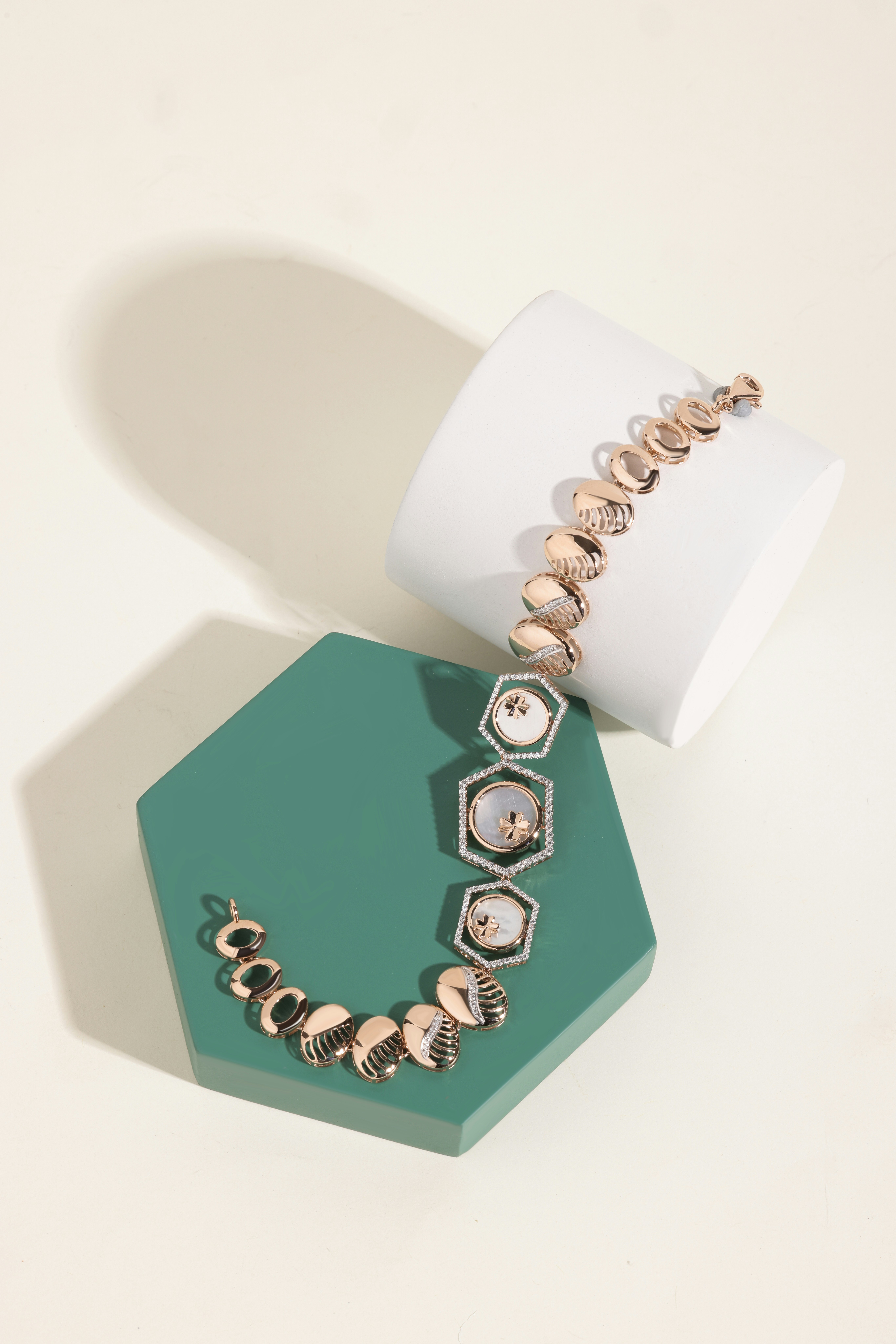 Gelang emas mawar dengan aksen mutiara di atas alas geometris display