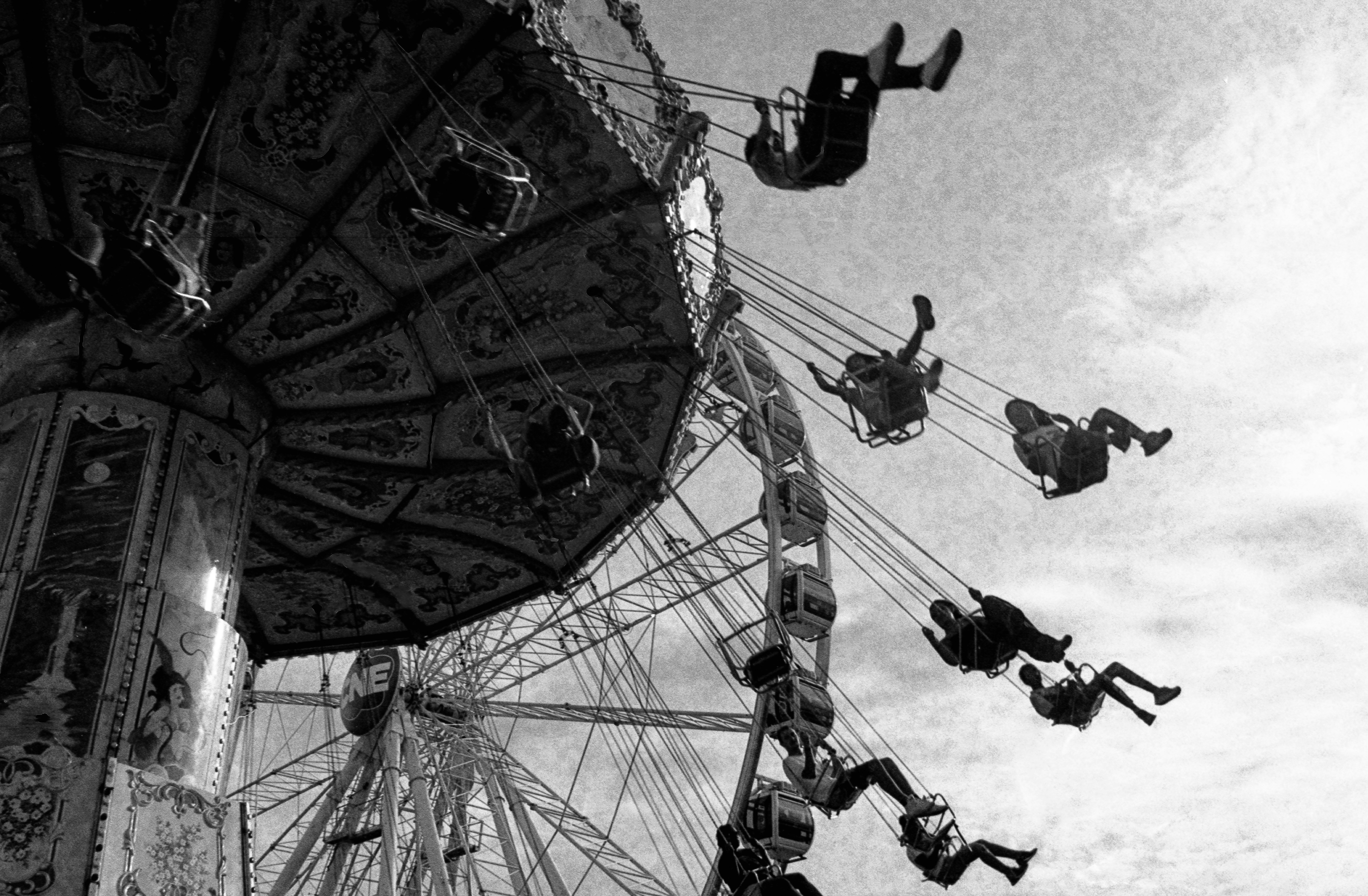 People riding a spinning swing carousel with a ferris wheel in the background