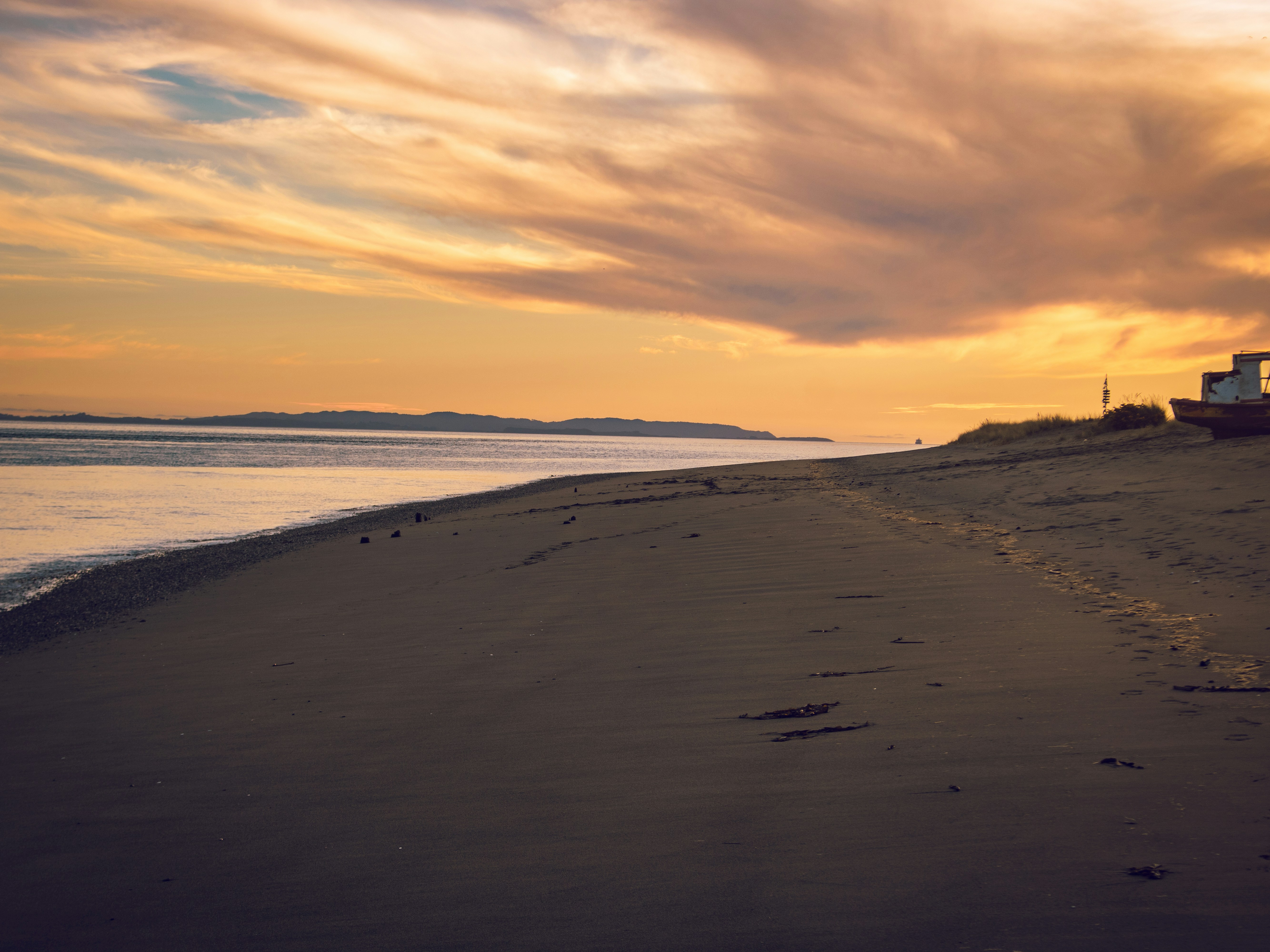 A sandy beach with a small boat under a warm orange sky