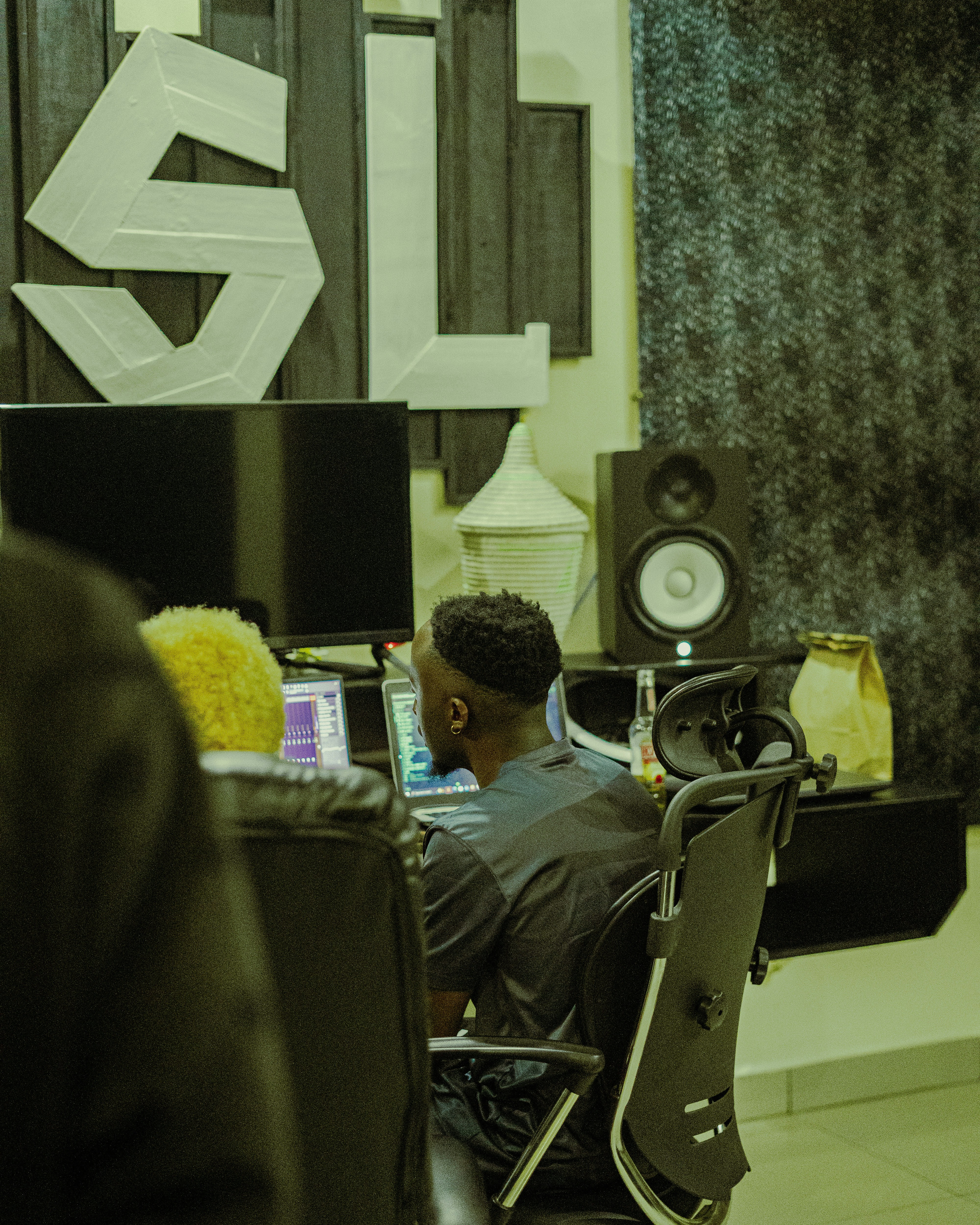 Two people working at computers in a music studio with sound equipment