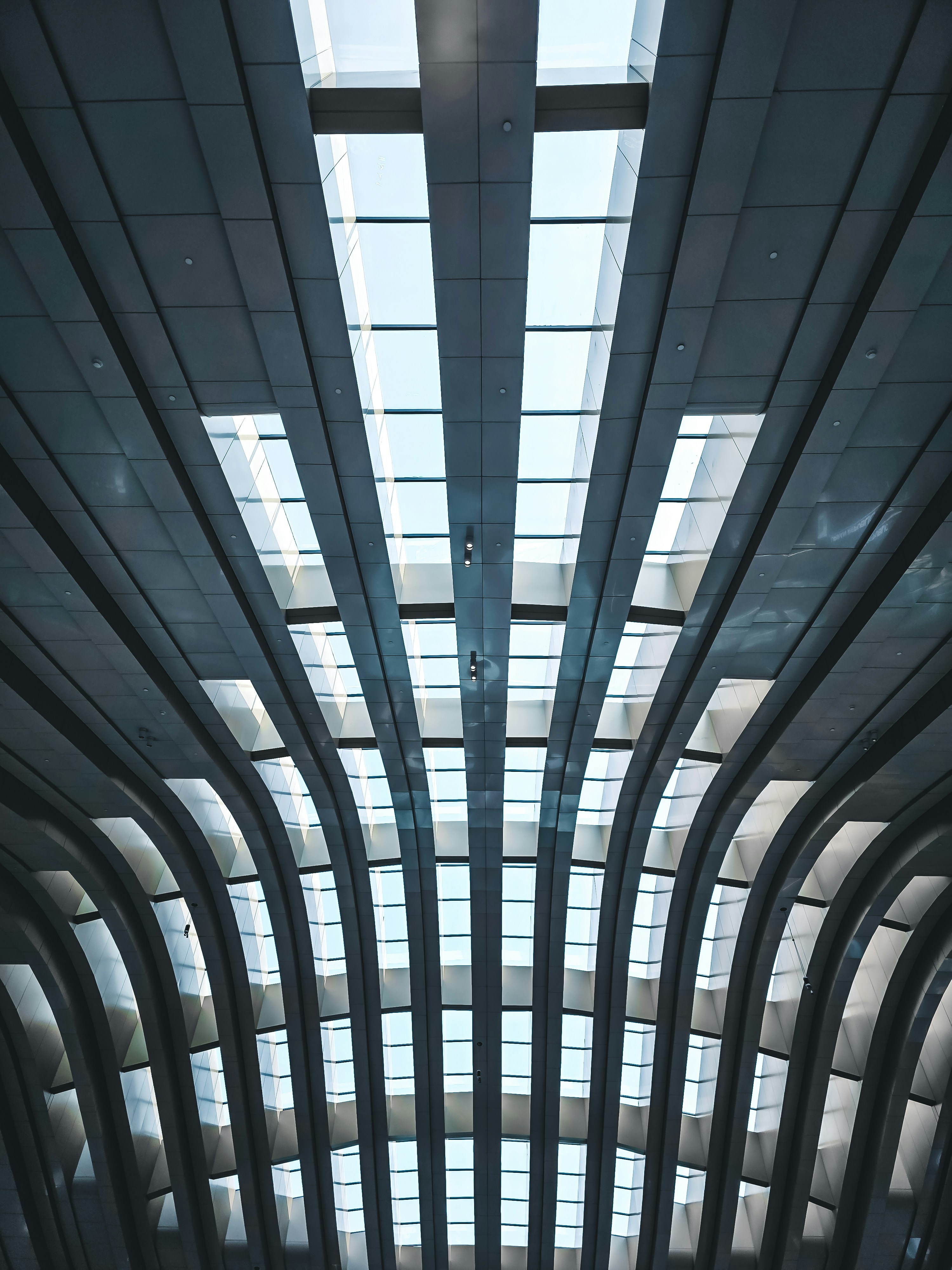 Curved metal beams forming a symmetrical ceiling structure with rectangular skylights