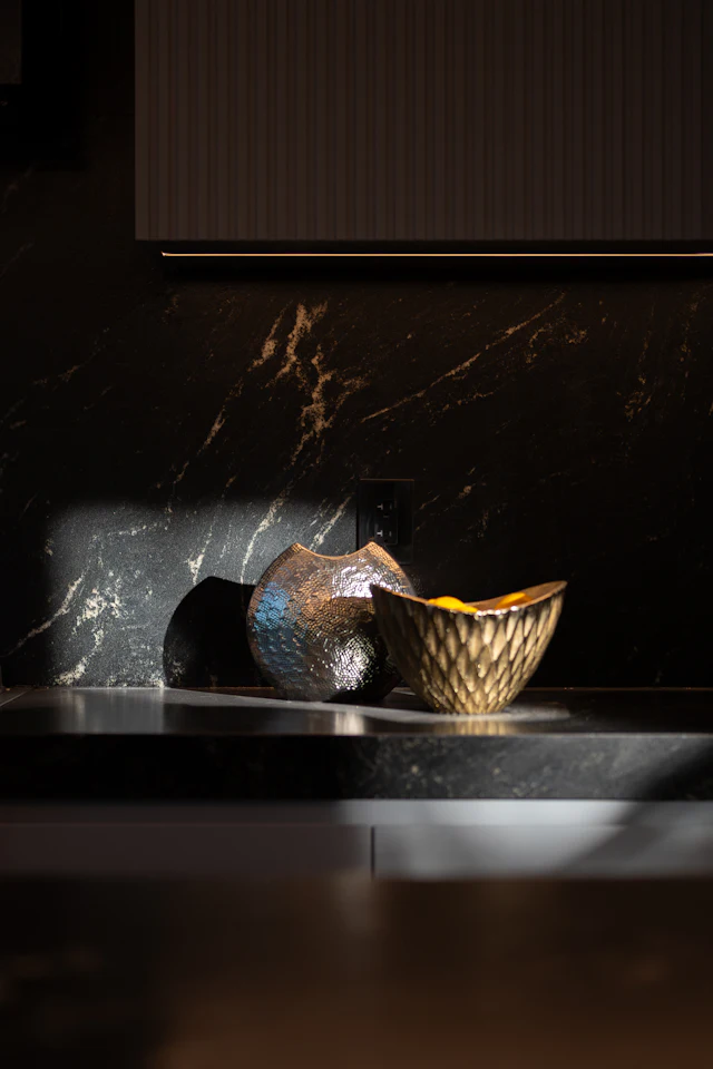 Black and gold Portoro-style marble counter and backsplash with a gold bowl