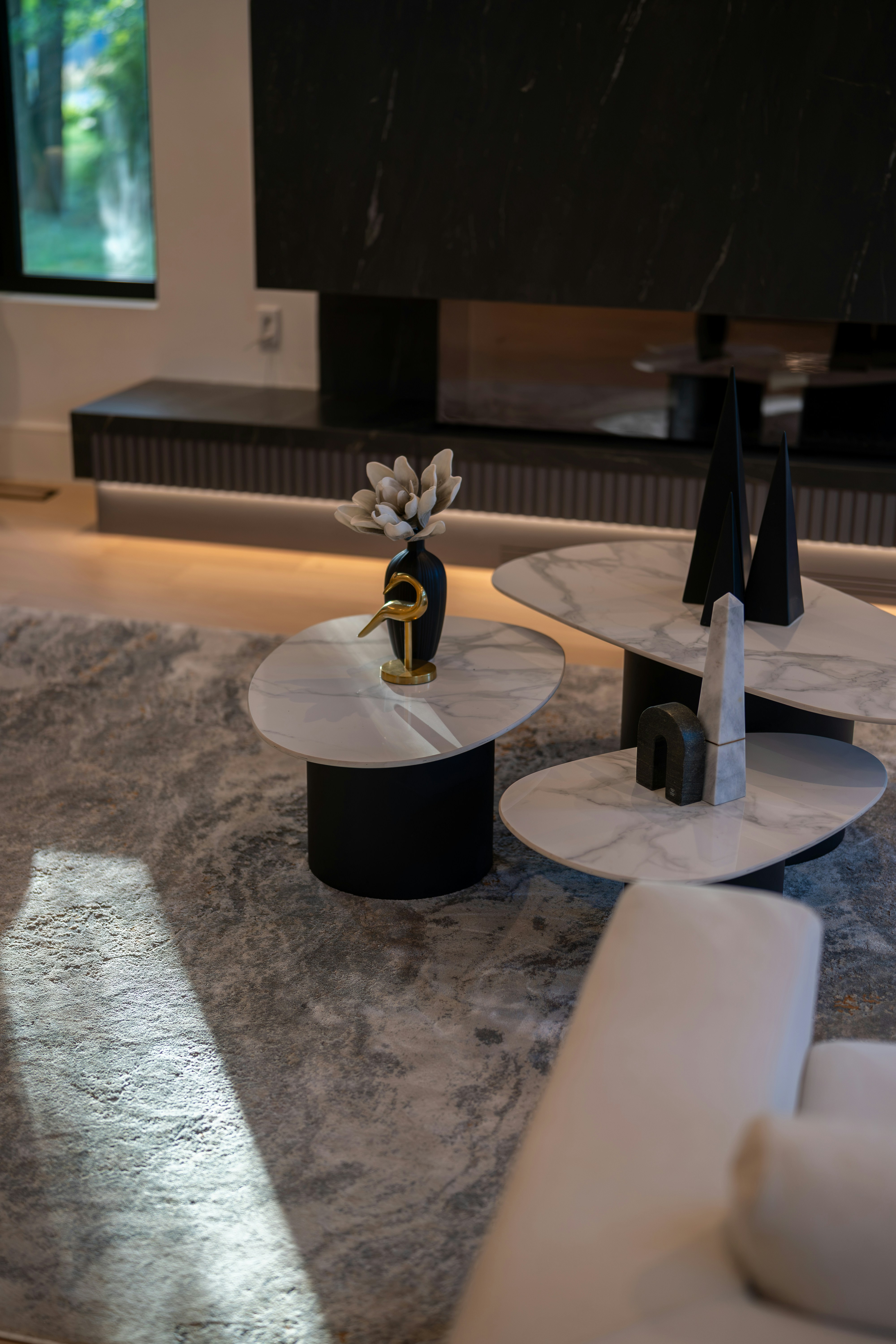 Three tiered marble coffee tables with decorative objects in a modern living room