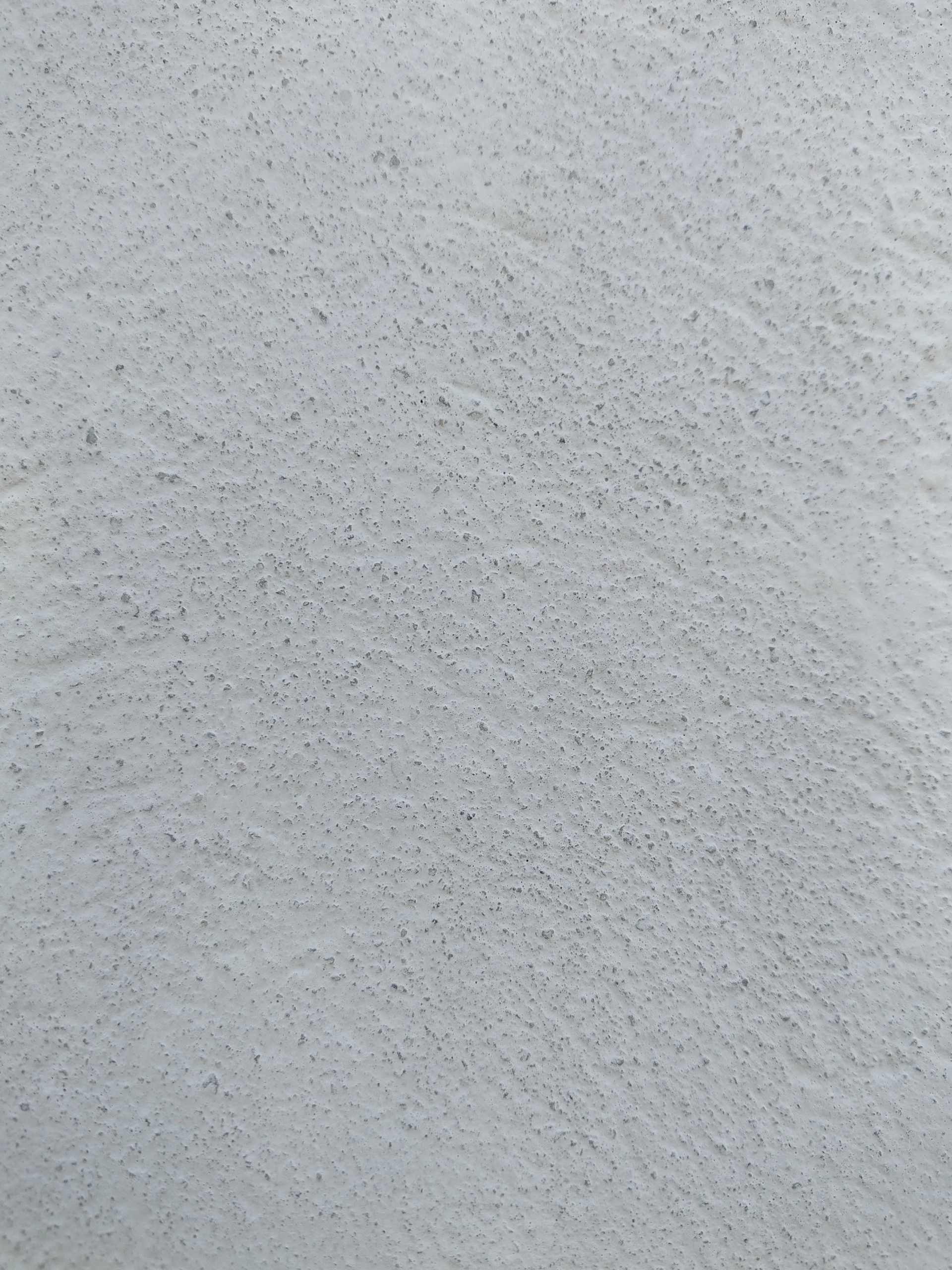 A white wall with a rough and granular plaster texture