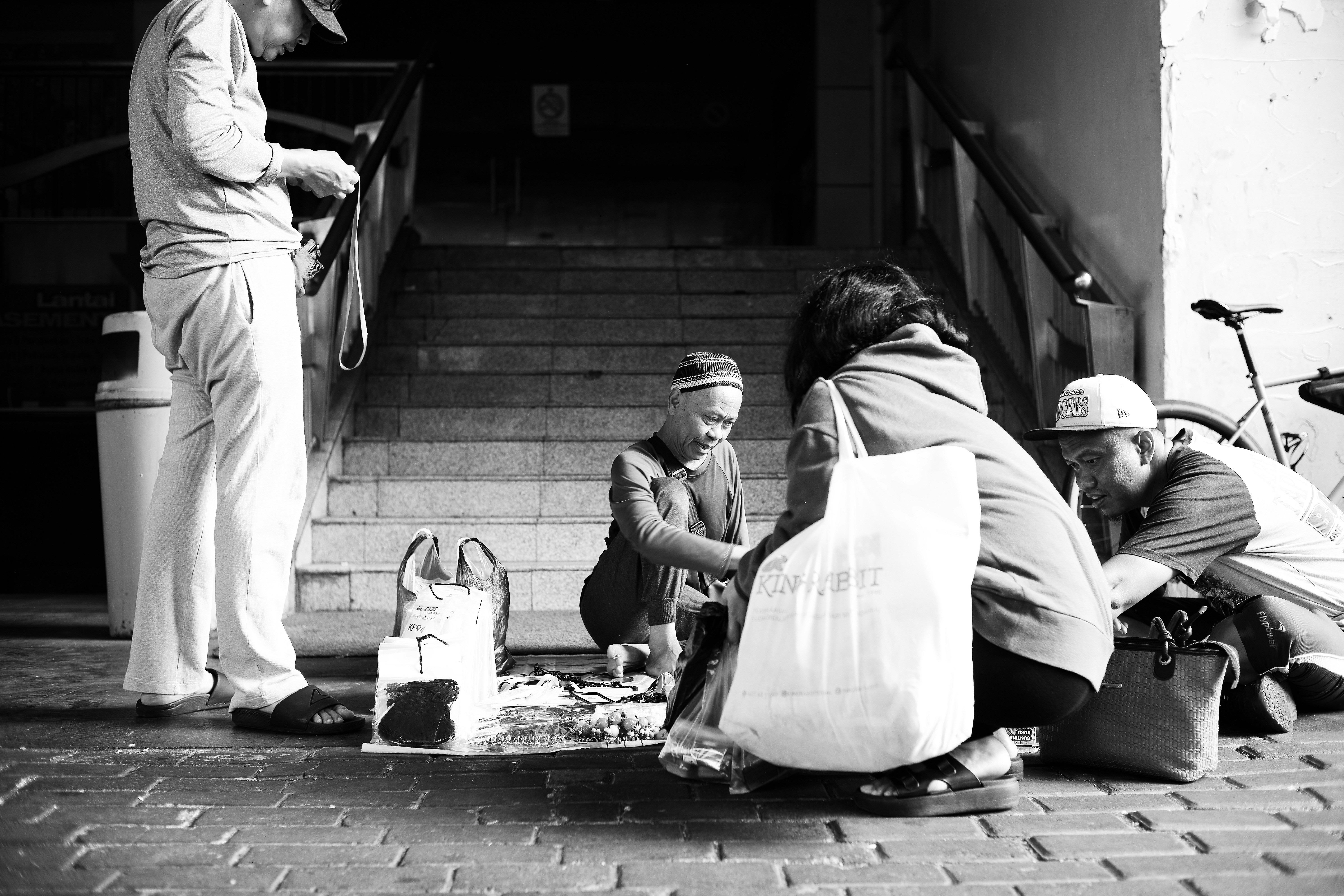 People gathered around a street vendor selling small items on a paved walkway