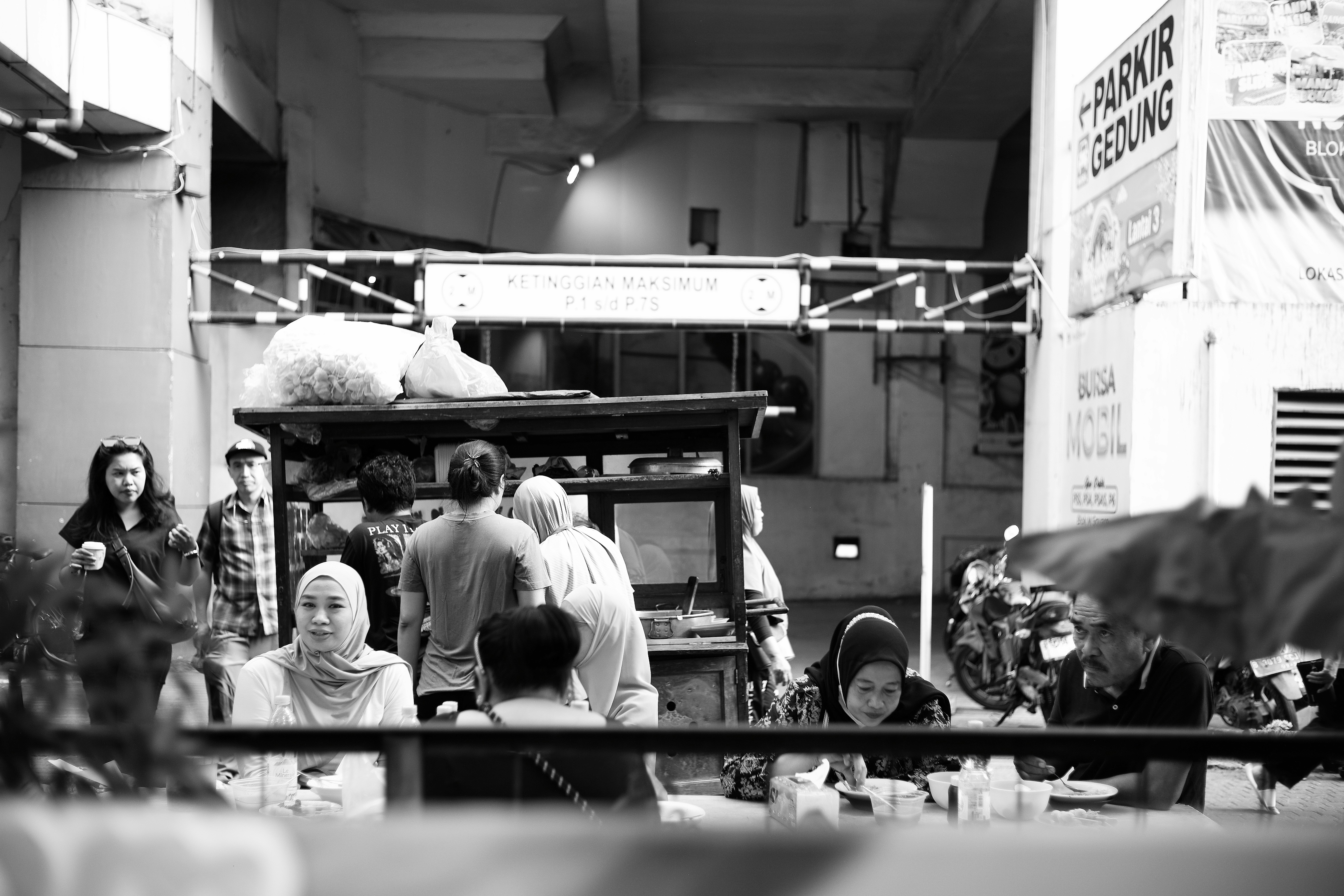 People eating at a street food stall in a parking garage area