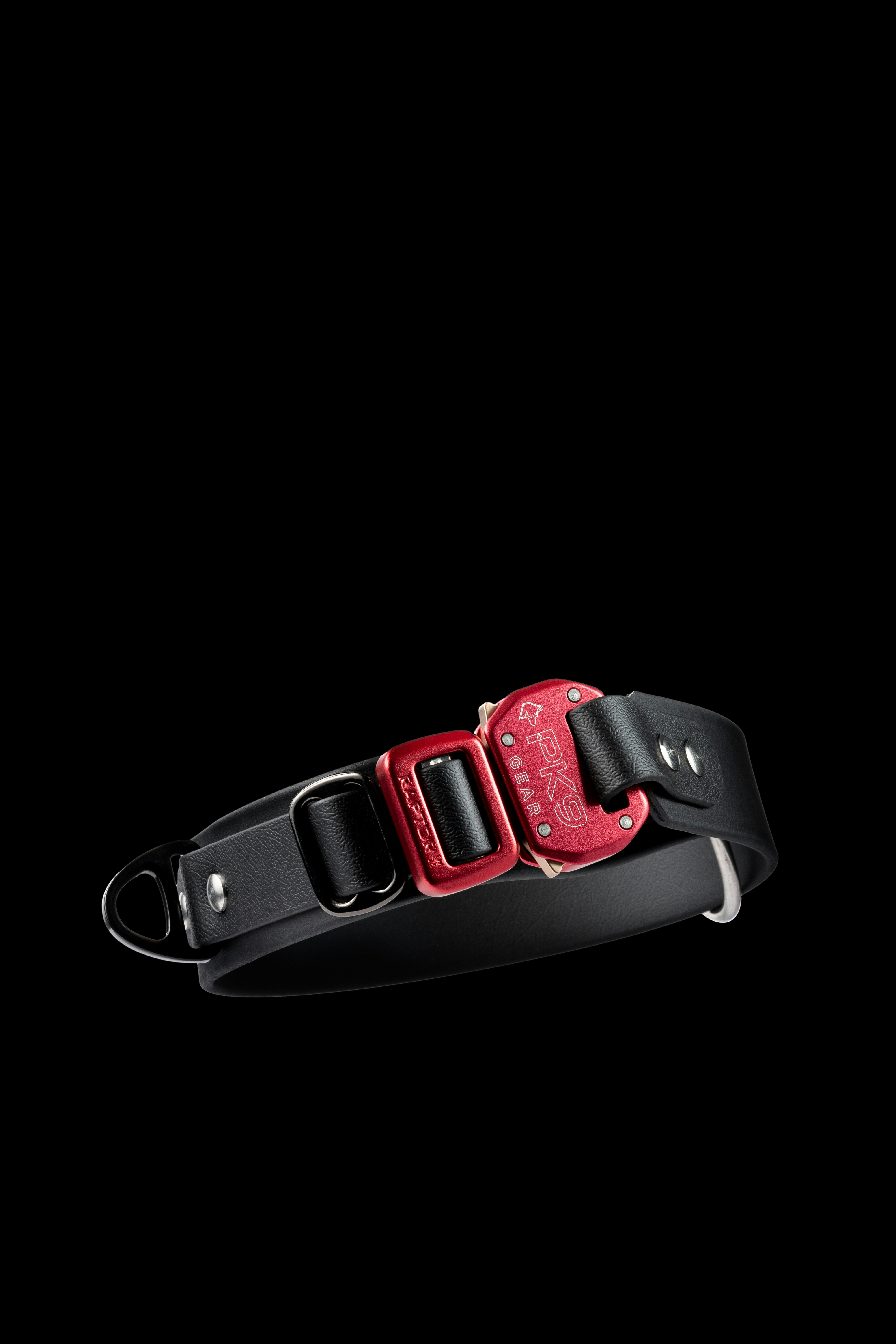 A black leather dog collar with a red metal buckle on a black background
