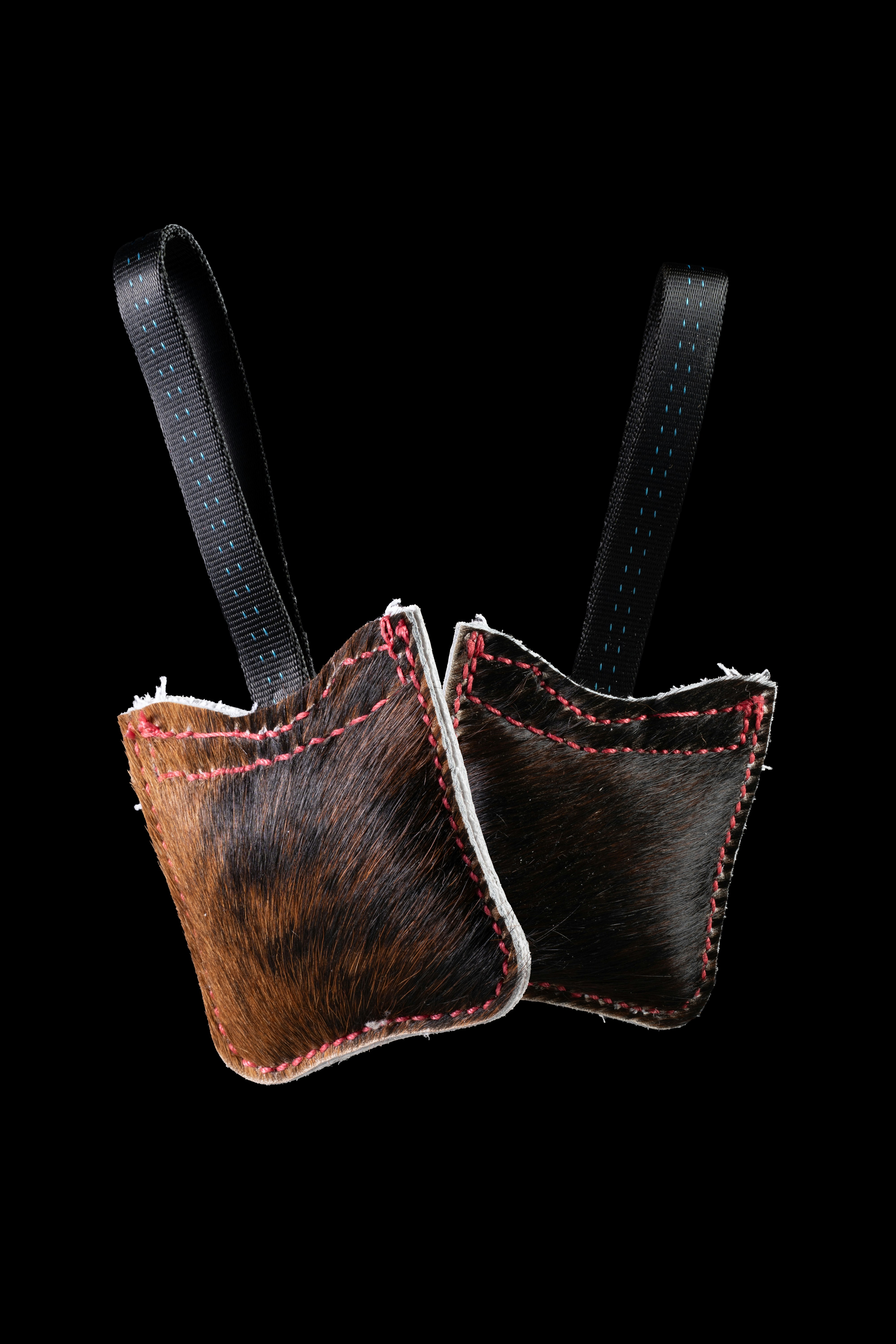 Two small pouches made of brown and black animal fur with red stitching