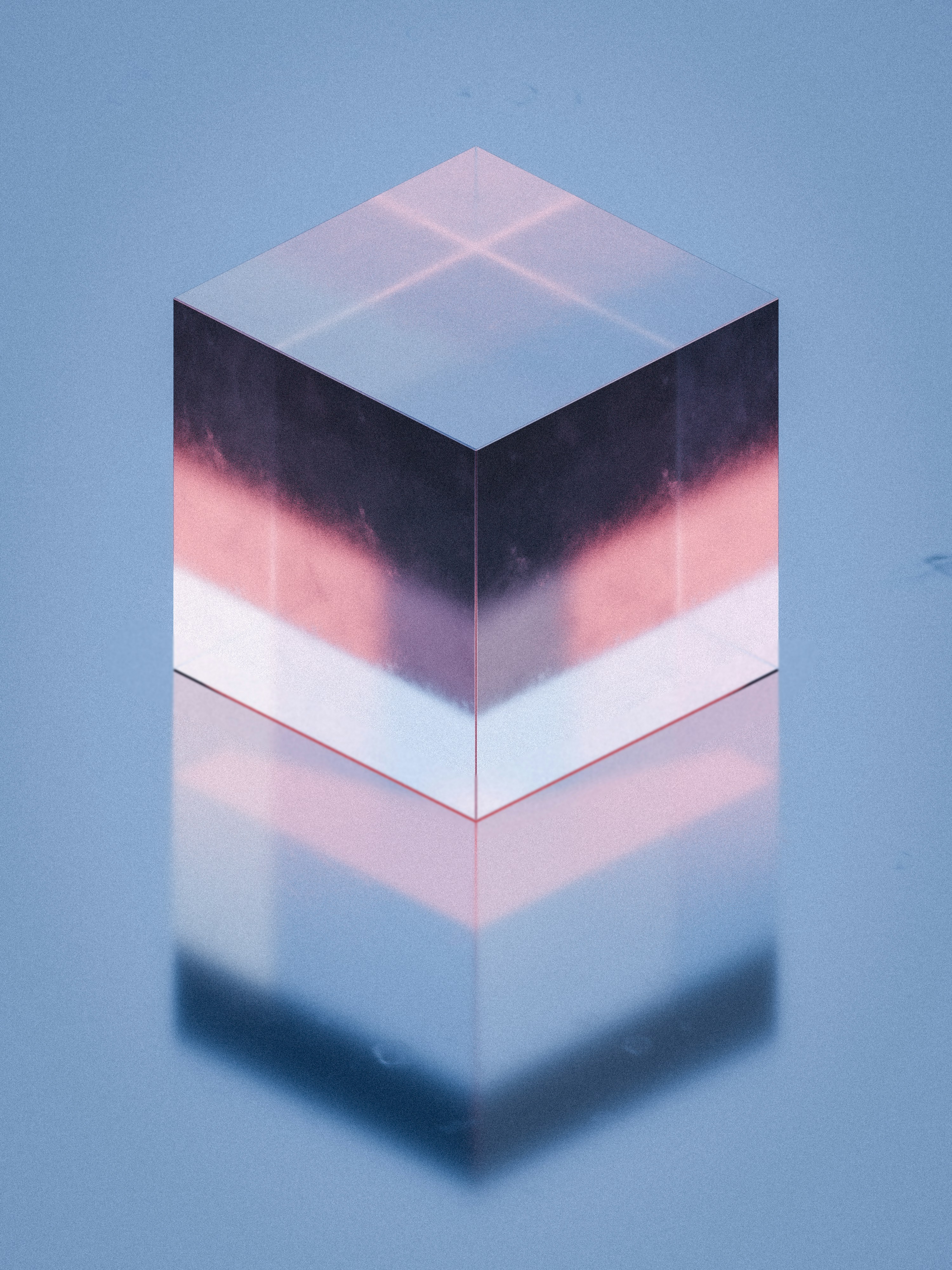 Ein durchscheinender Glaswürfel mit rosa und dunklen Farbverläufen, die sich auf einer blauen Oberfläche spiegeln