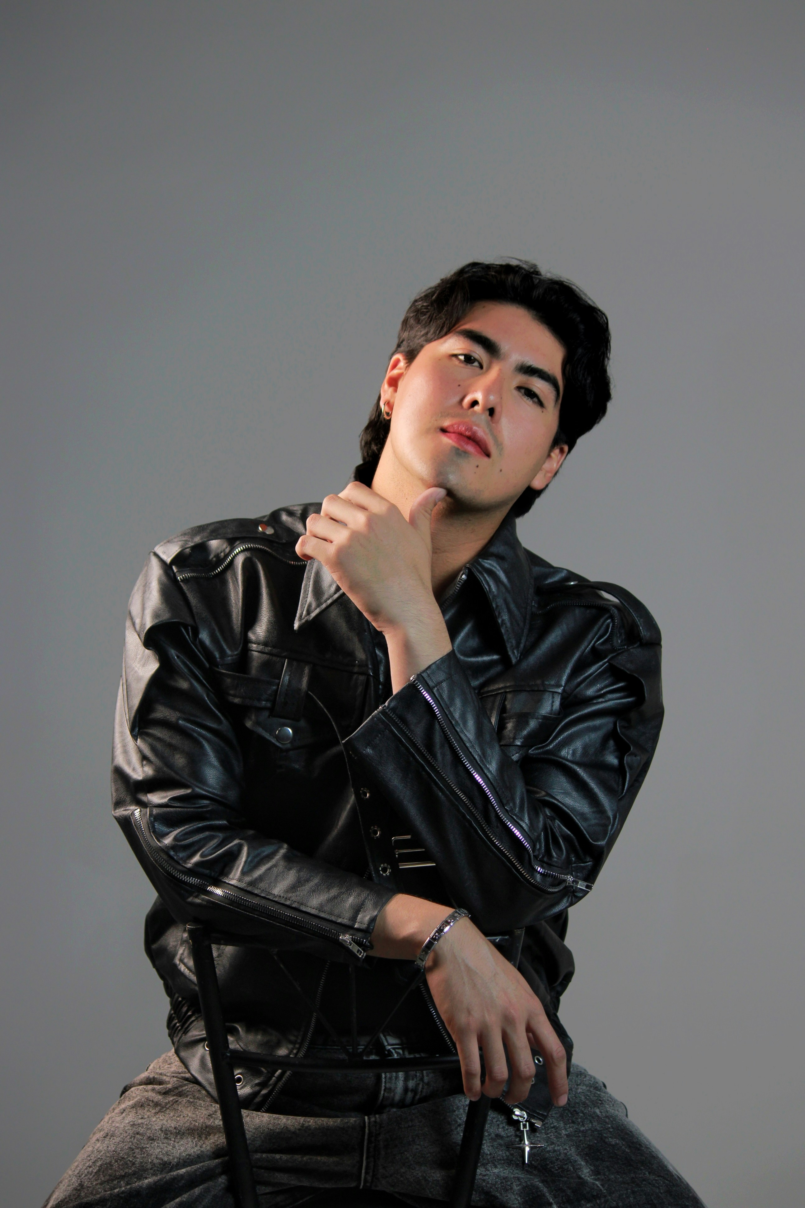 A man in a black leather jacket resting his chin on his hand