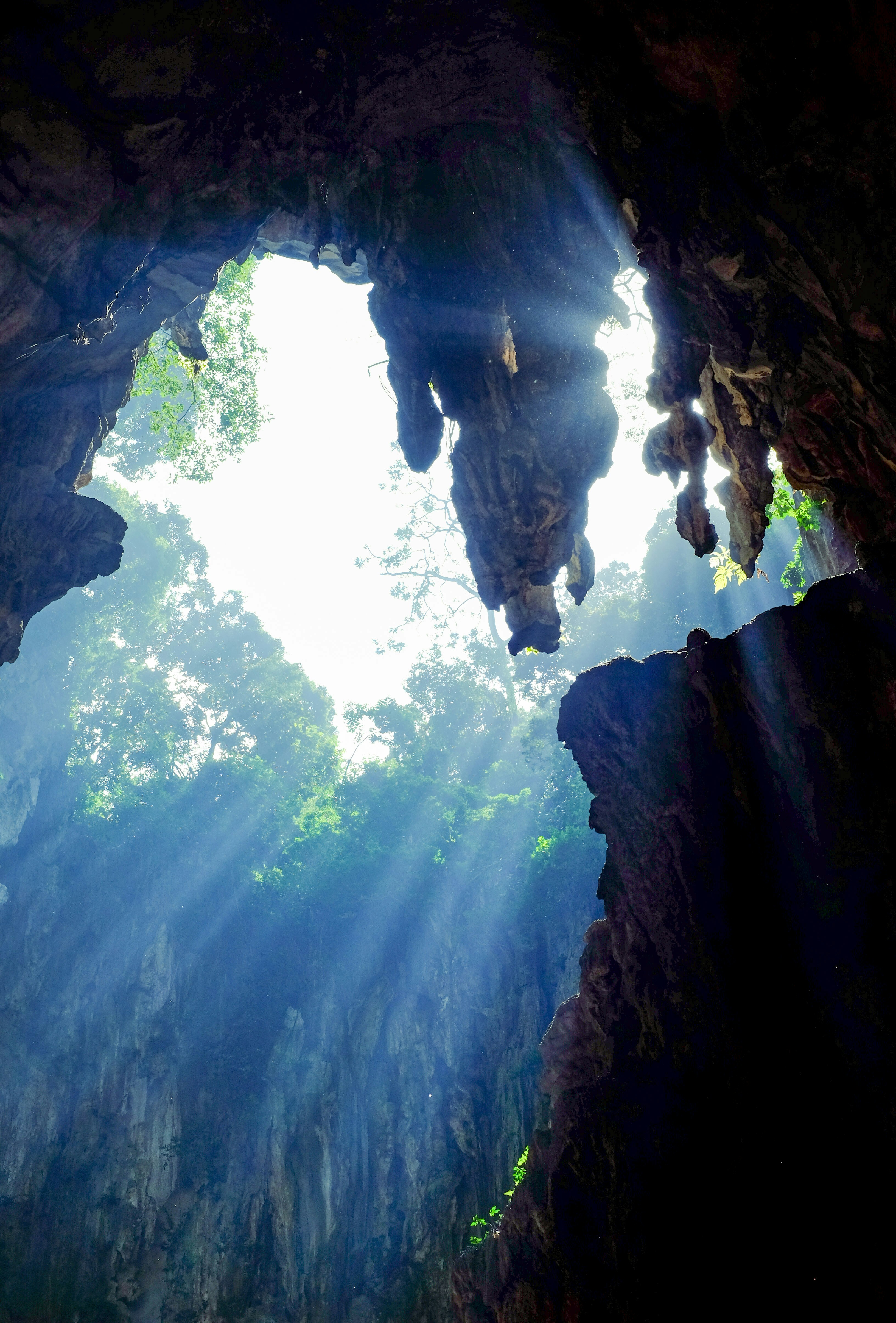 A luz do sol entrando por uma grande abertura no teto de uma caverna de calcário