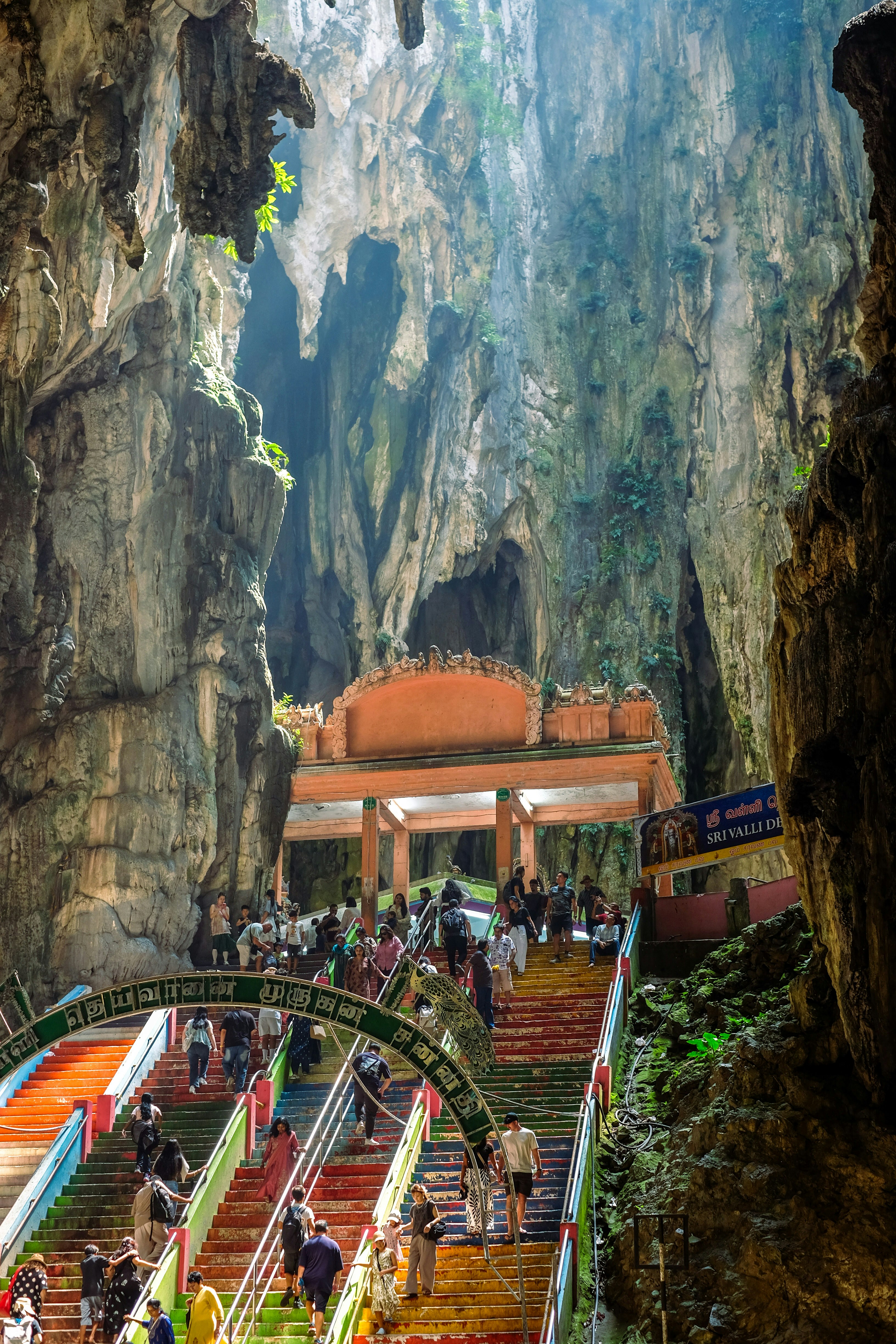 Pessoas subindo escadas coloridas dentro das cavernas de calcário Batu em Gombak, Malásia