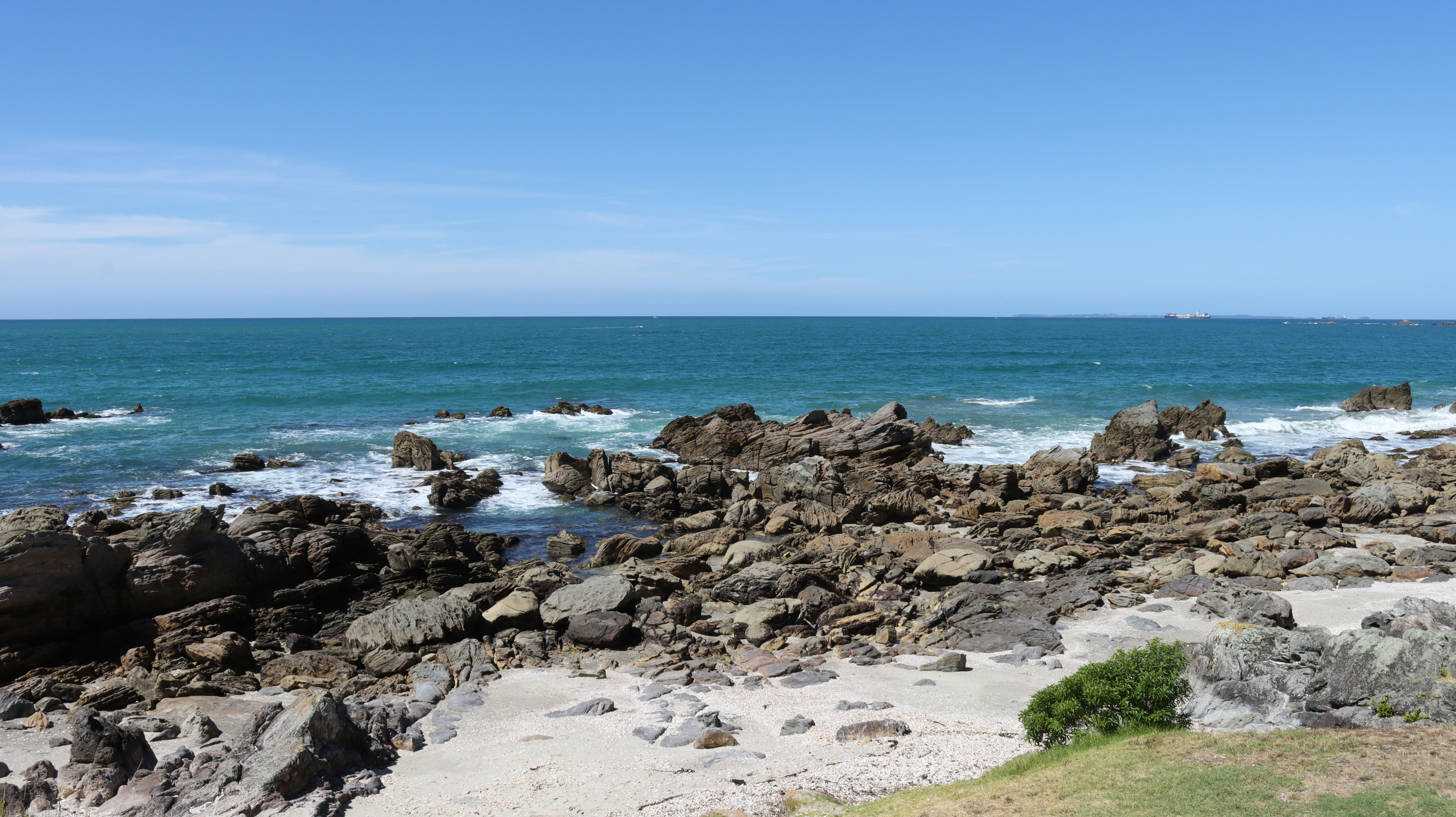 Rocky coastline with white sand and turquoise water under a clear blue sky