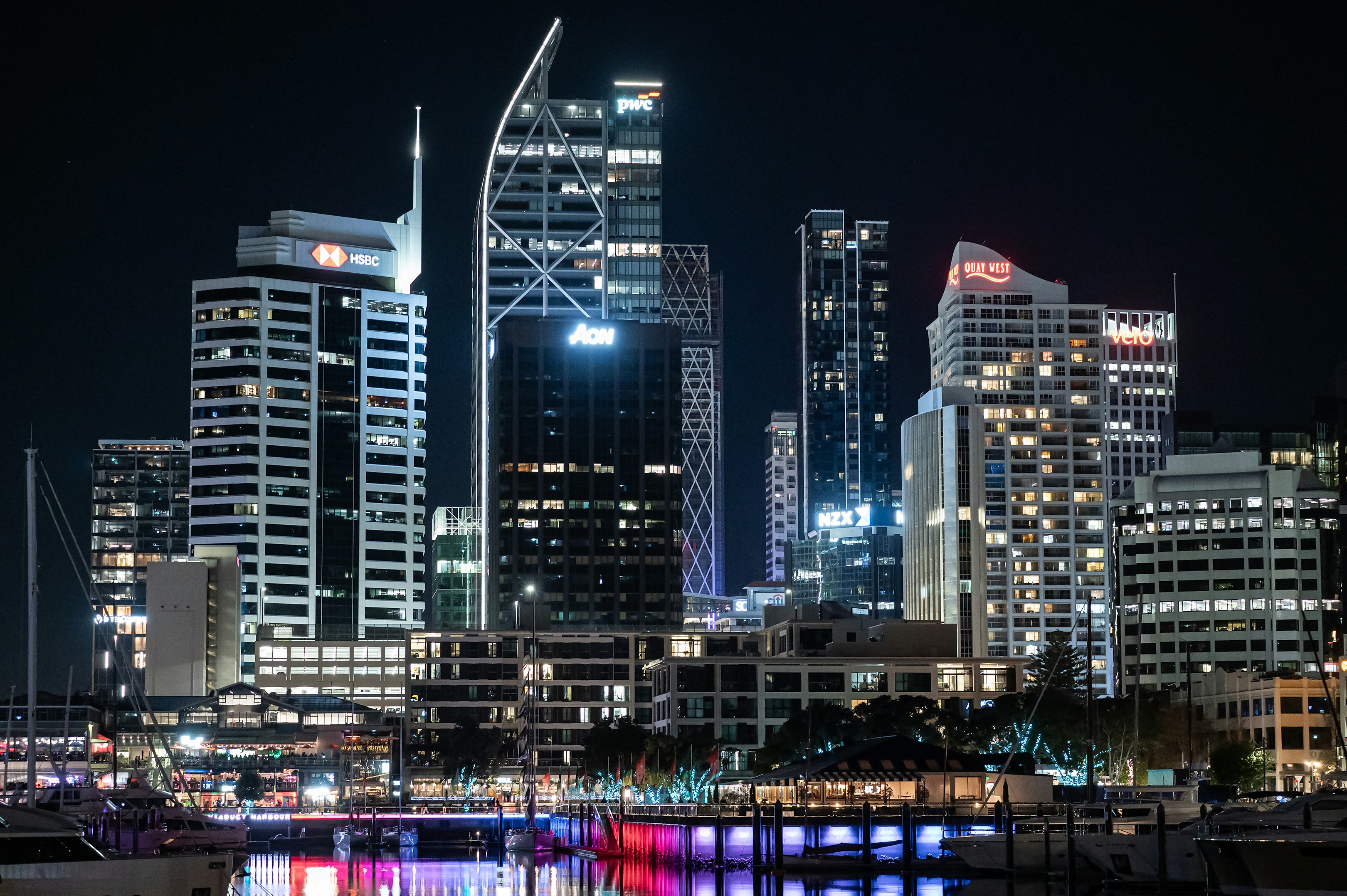 Illuminated skyscrapers at night reflecting in the dark water of Viaduct Harbour in Auckland