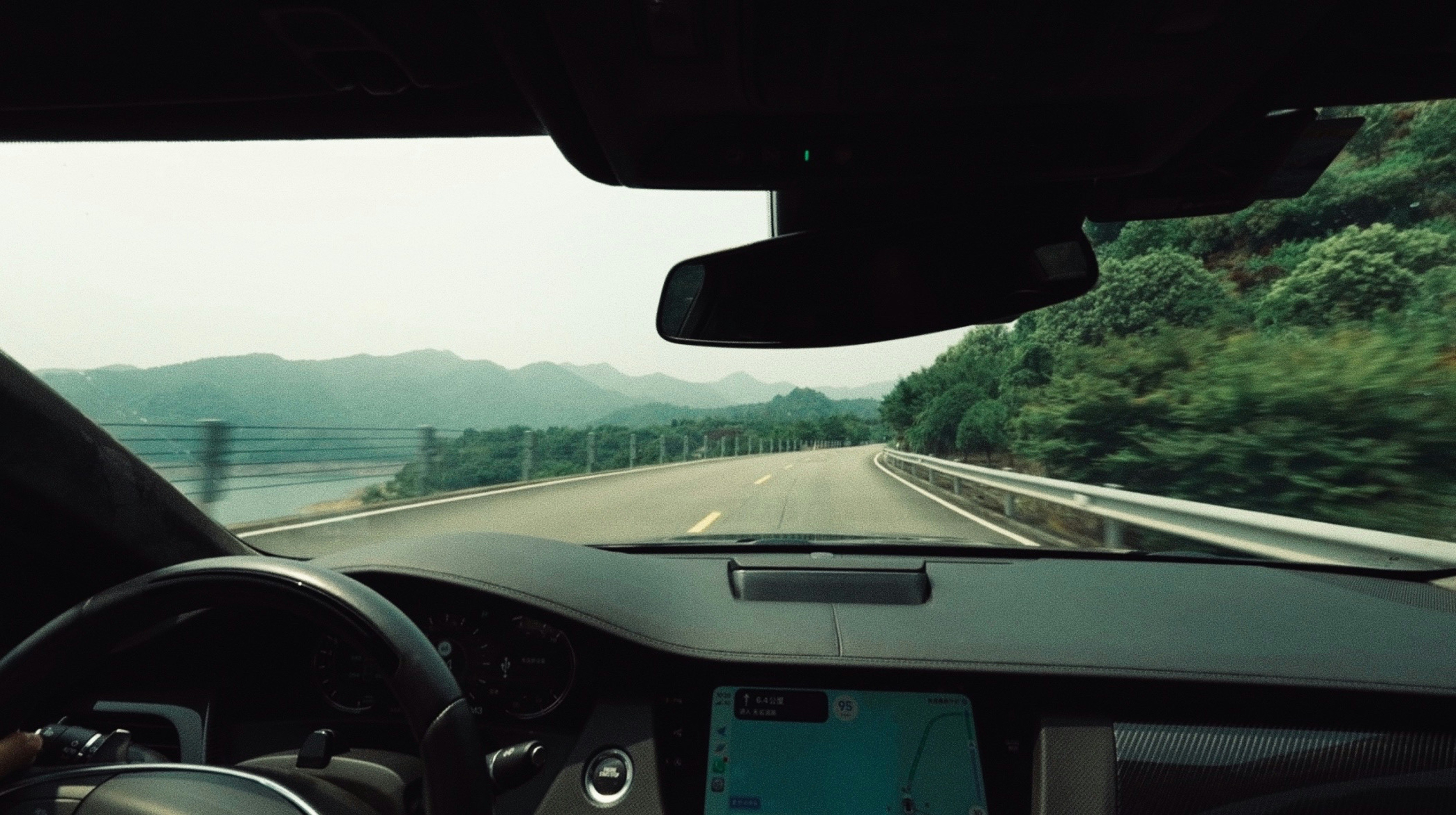 A view from inside a car driving along a winding road near mountains