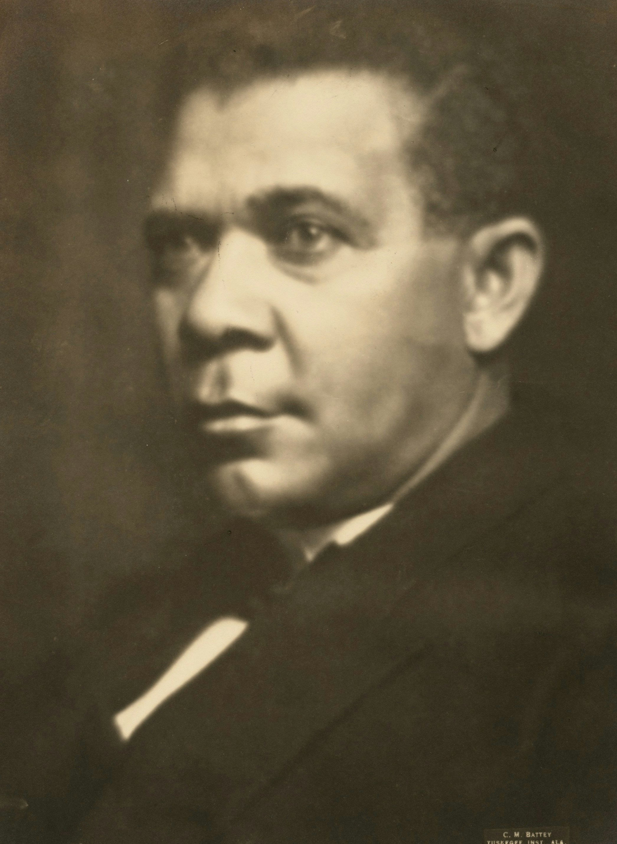 A portrait of a man in a dark suit and white shirt