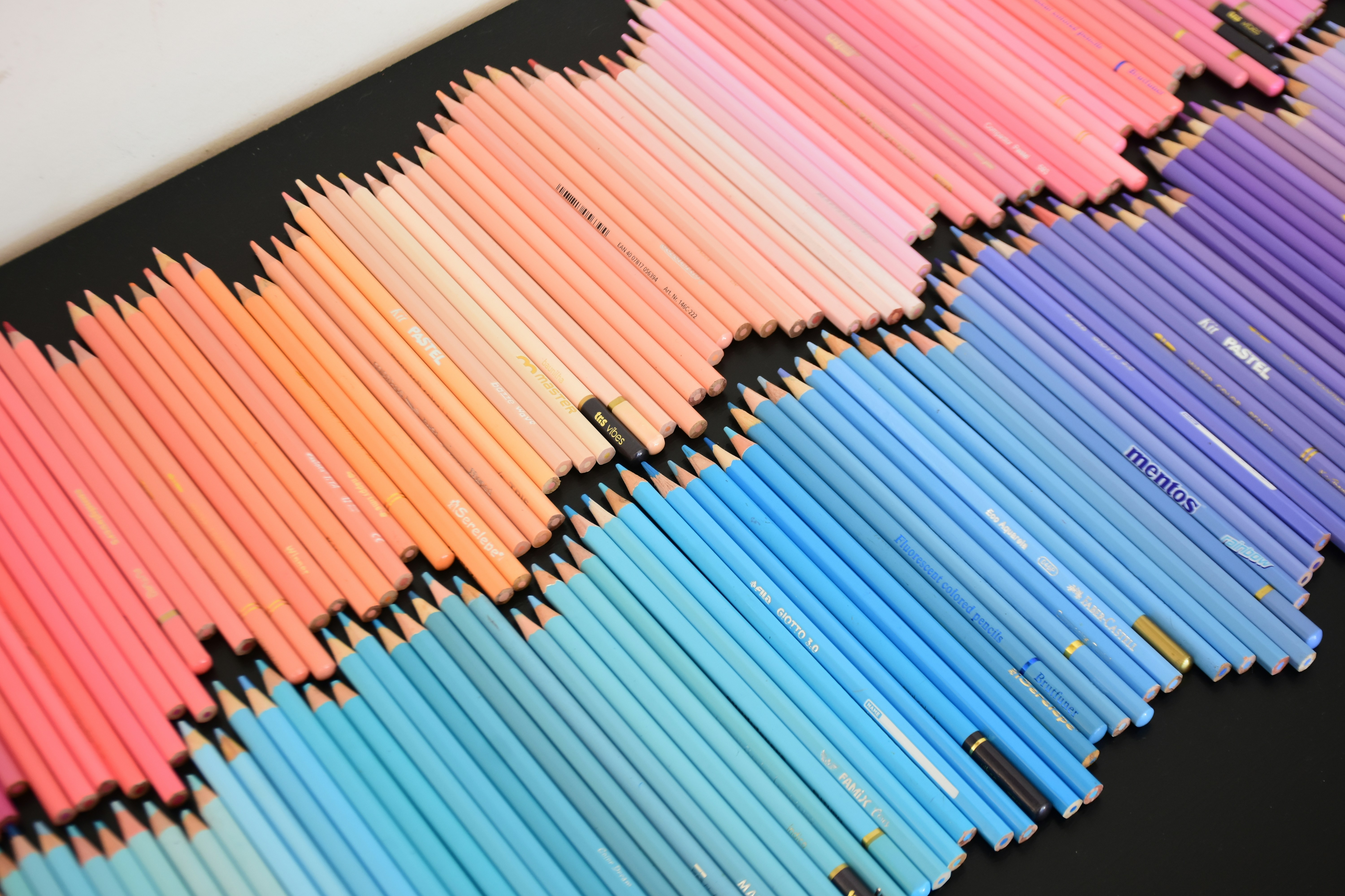 Une collection de crayons de couleur disposés en dégradé sur une surface noire