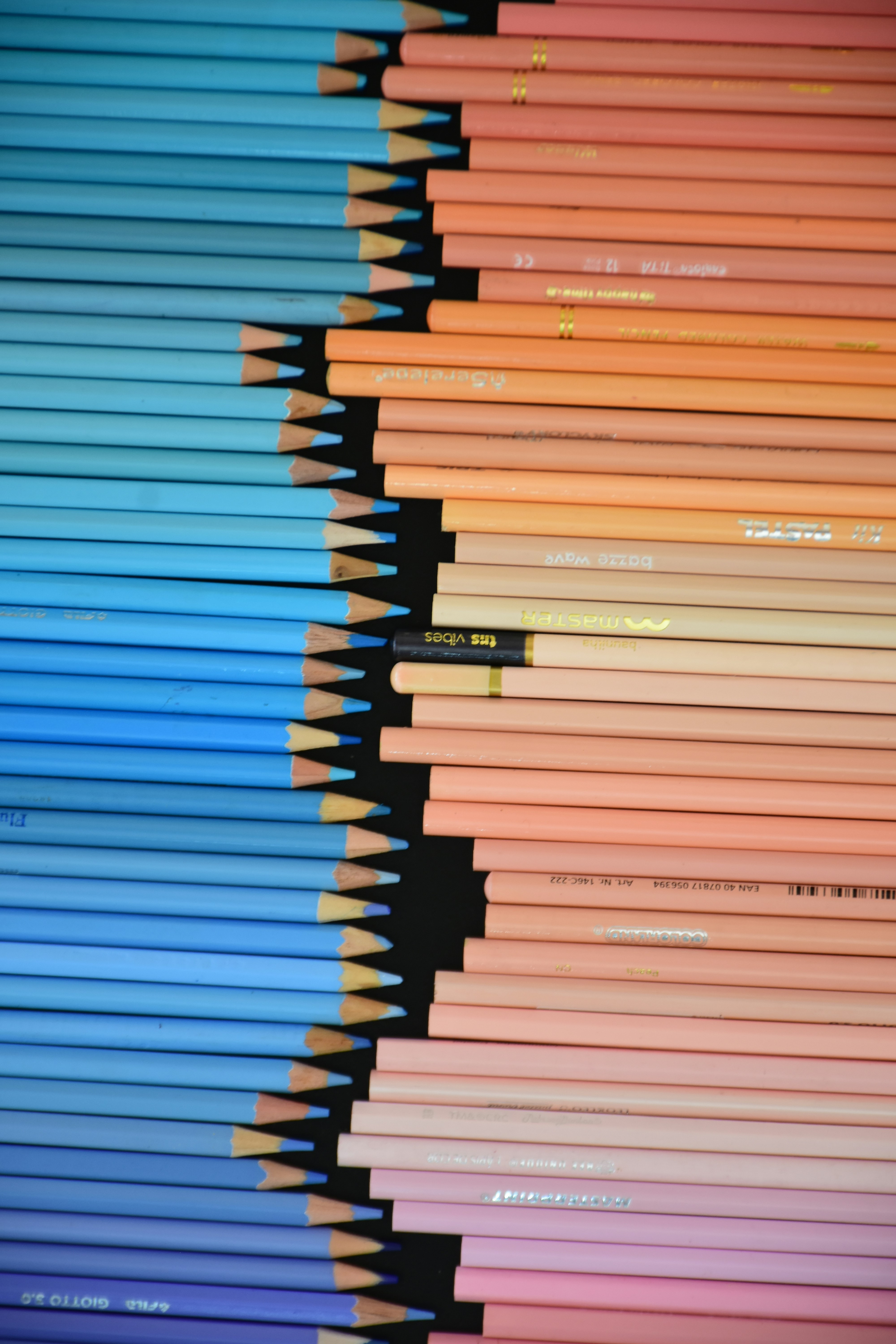 Blue and peach colored pencils arranged in two columns on a black background